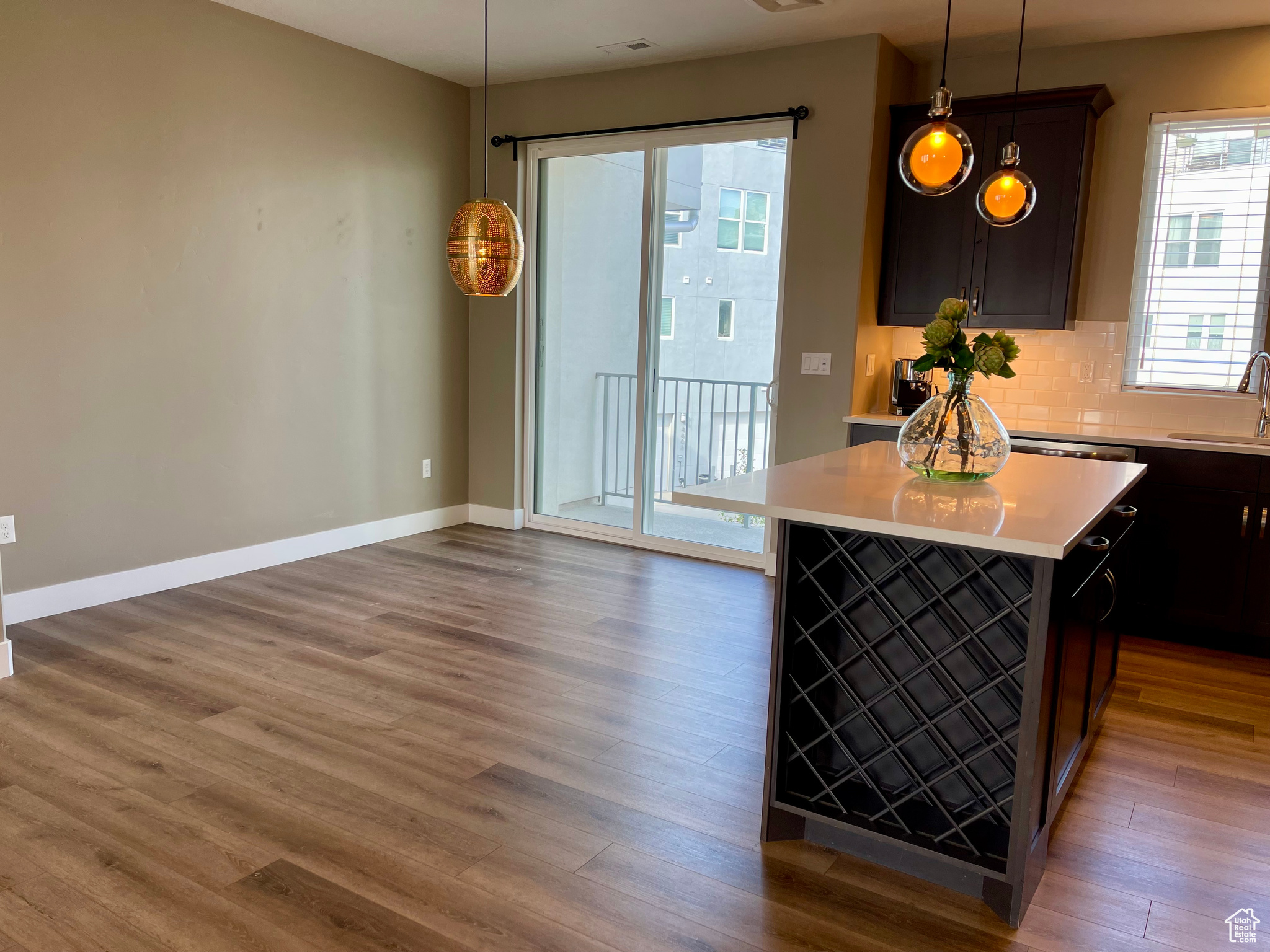 Kitchen featuring pendant lighting, hardwood / wood-style floors, dark brown cabinets, a kitchen island, and sink