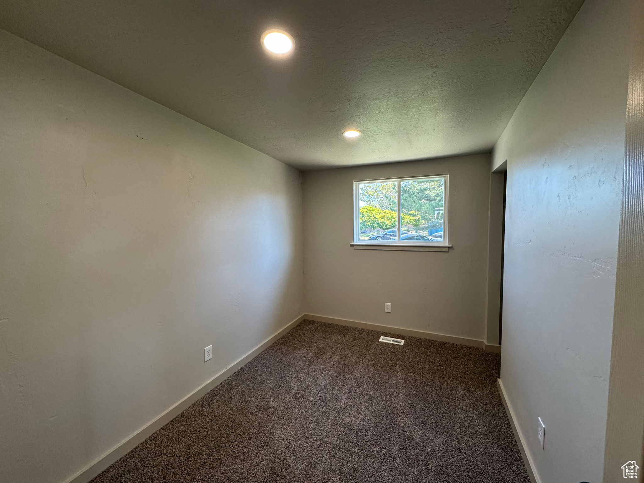 Carpeted spare room with a textured ceiling