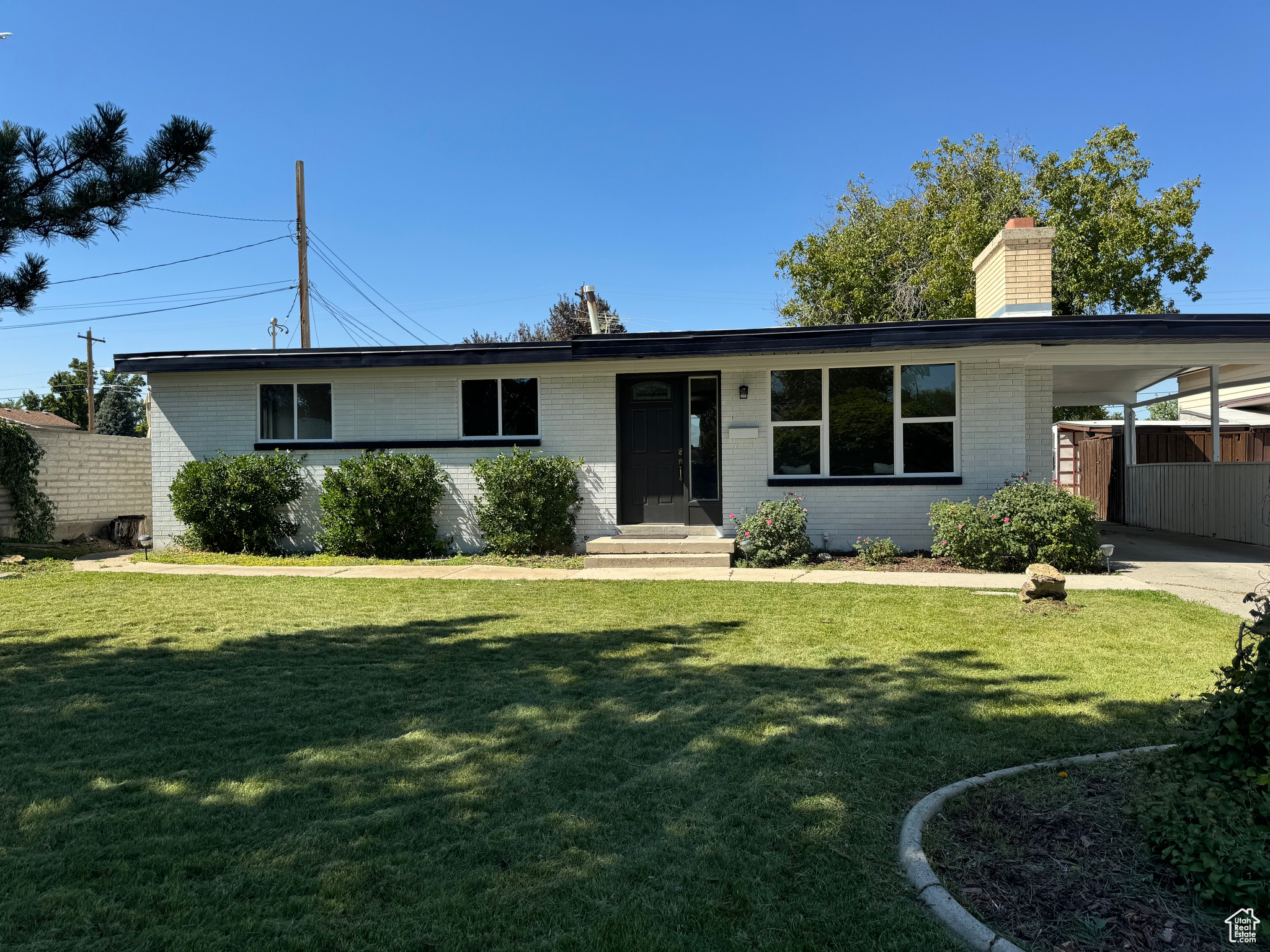 View of front of property with a carport and a front lawn