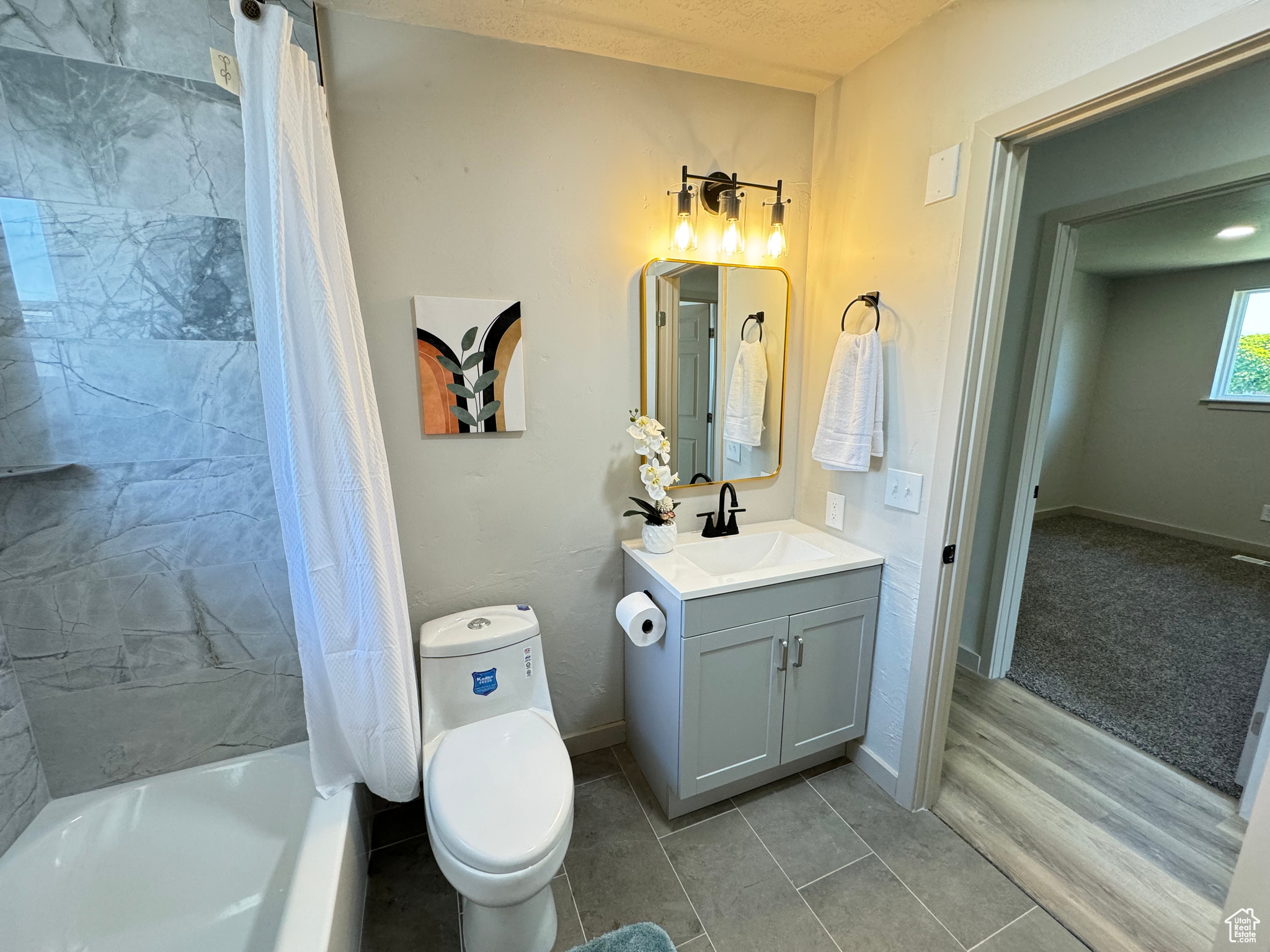 Full bathroom with hardwood / wood-style flooring, shower / bathtub combination with curtain, toilet, vanity, and a textured ceiling