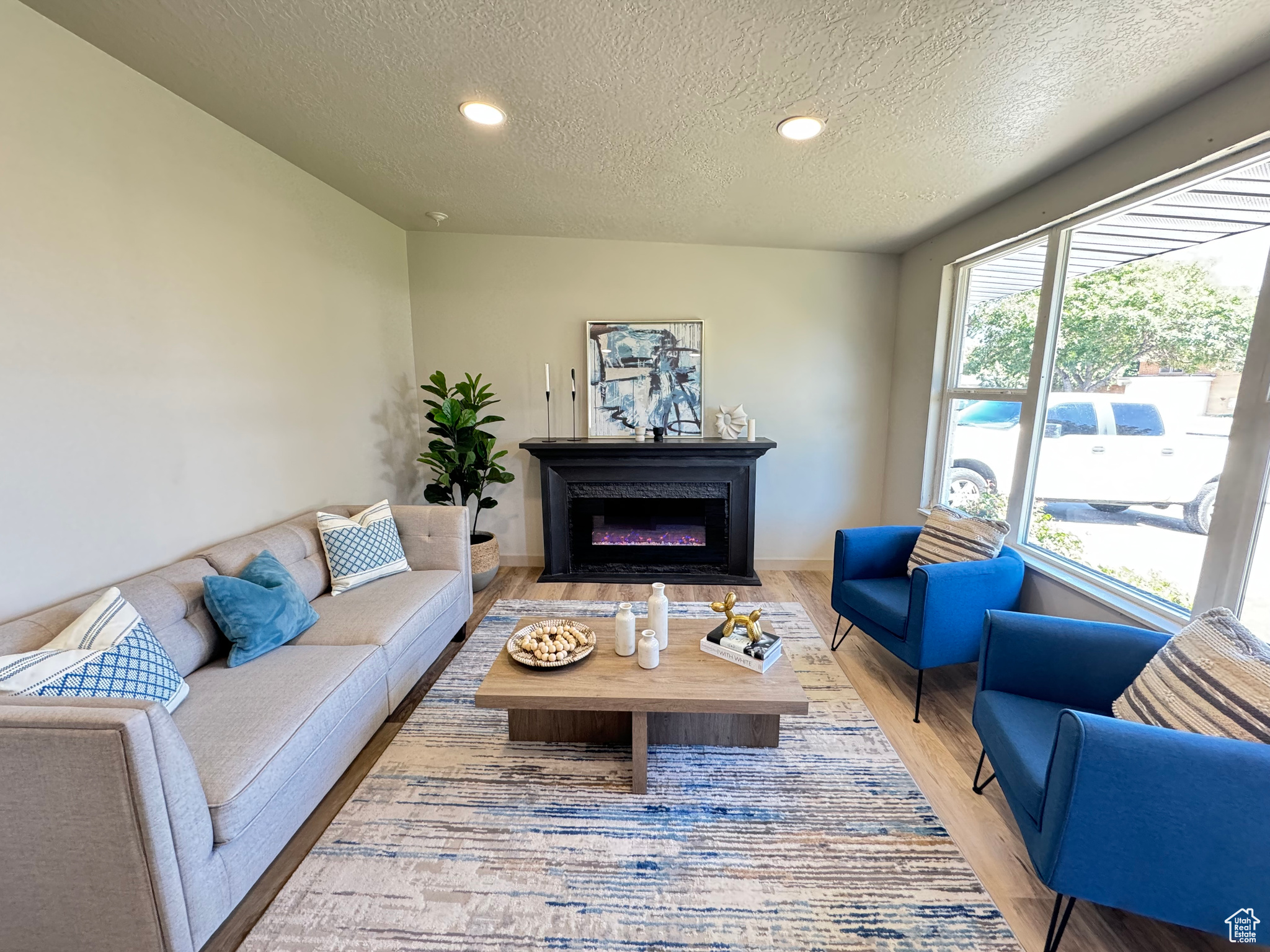 Living room with a textured ceiling and light hardwood / wood-style floors