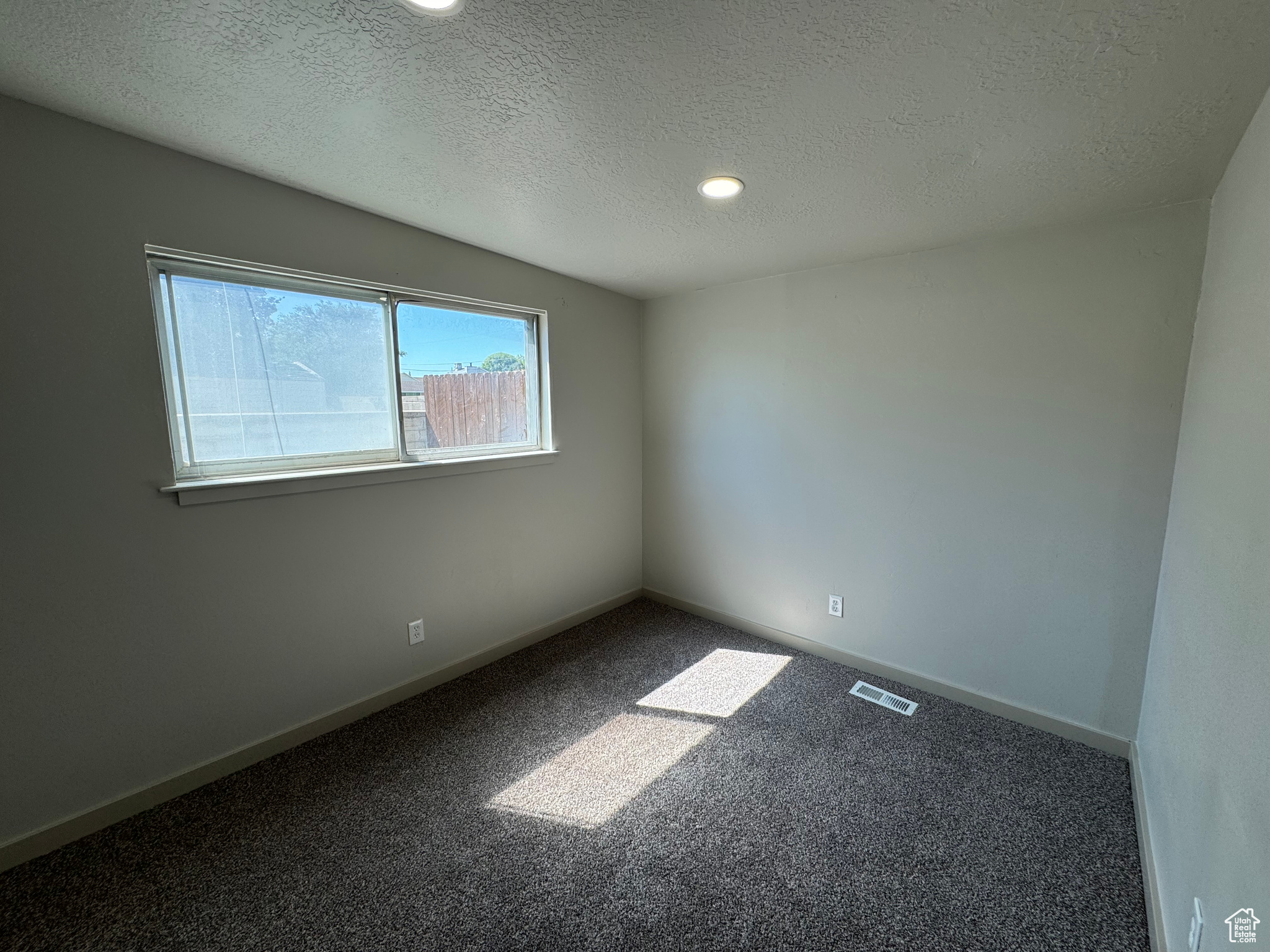 Carpeted spare room with a textured ceiling