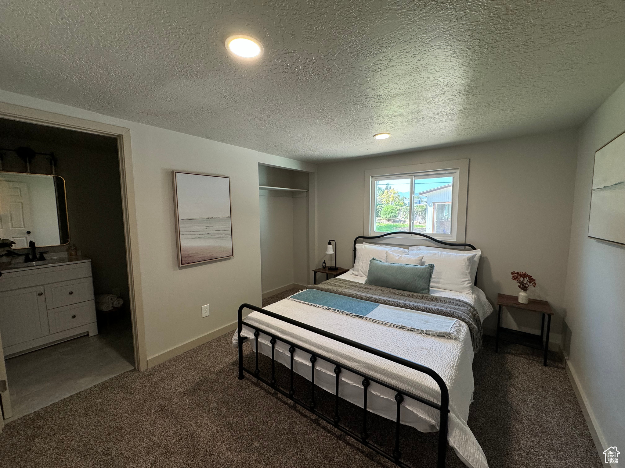 Bedroom featuring dark colored carpet, sink, and a textured ceiling