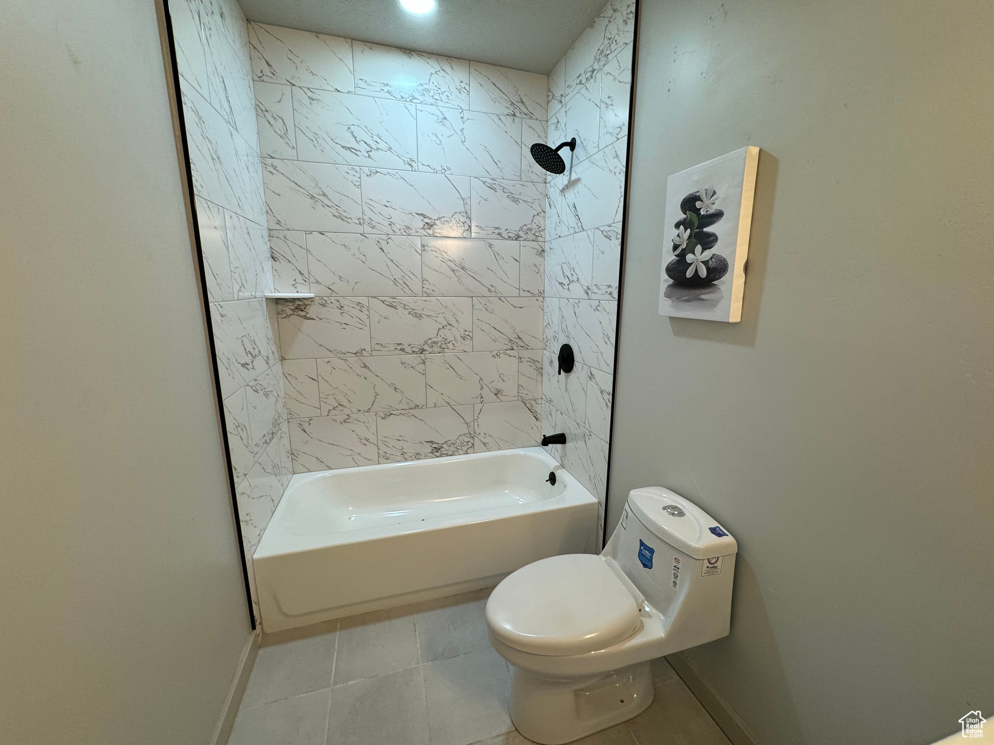 Bathroom with tiled shower / bath combo, toilet, and tile patterned floors