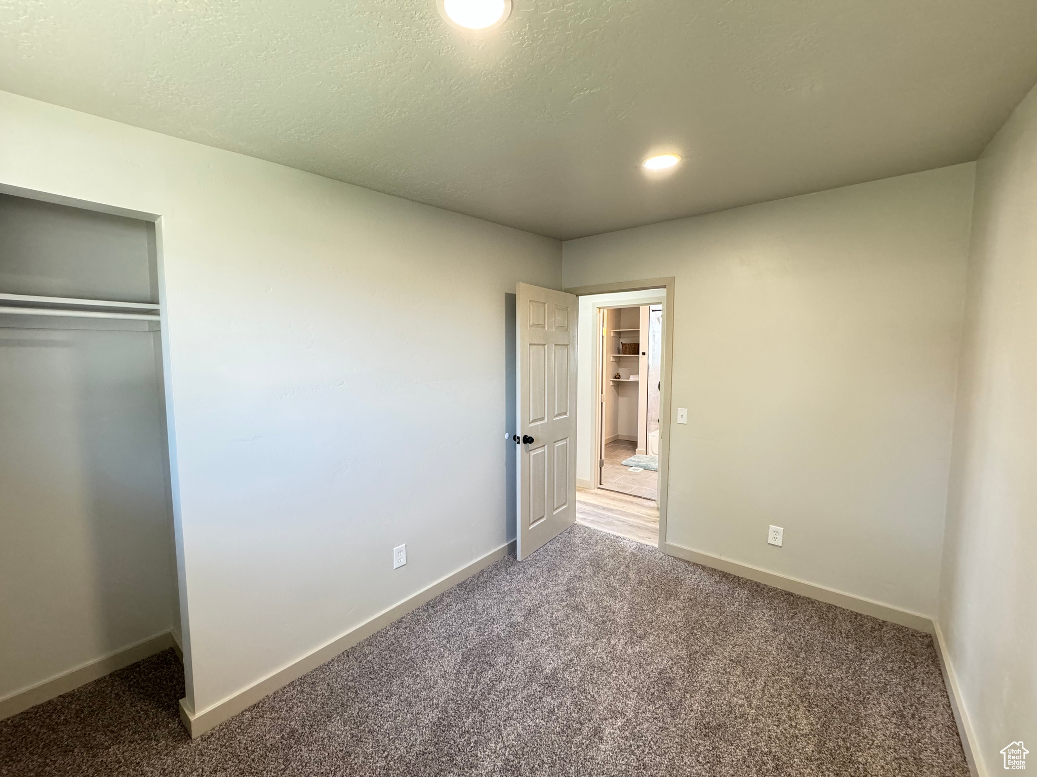 Unfurnished bedroom with a textured ceiling, carpet flooring, and a closet