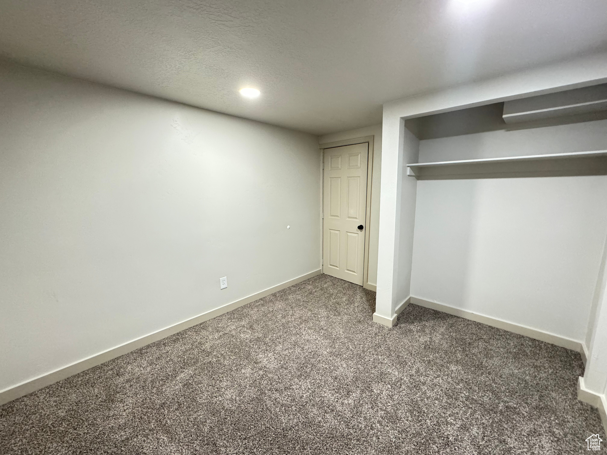 Unfurnished bedroom featuring a textured ceiling, dark carpet, and a closet