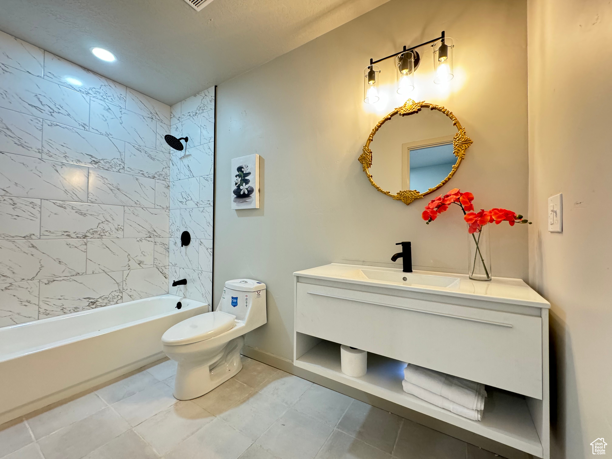 Full bathroom featuring tile patterned flooring, toilet, tiled shower / bath combo, and vanity