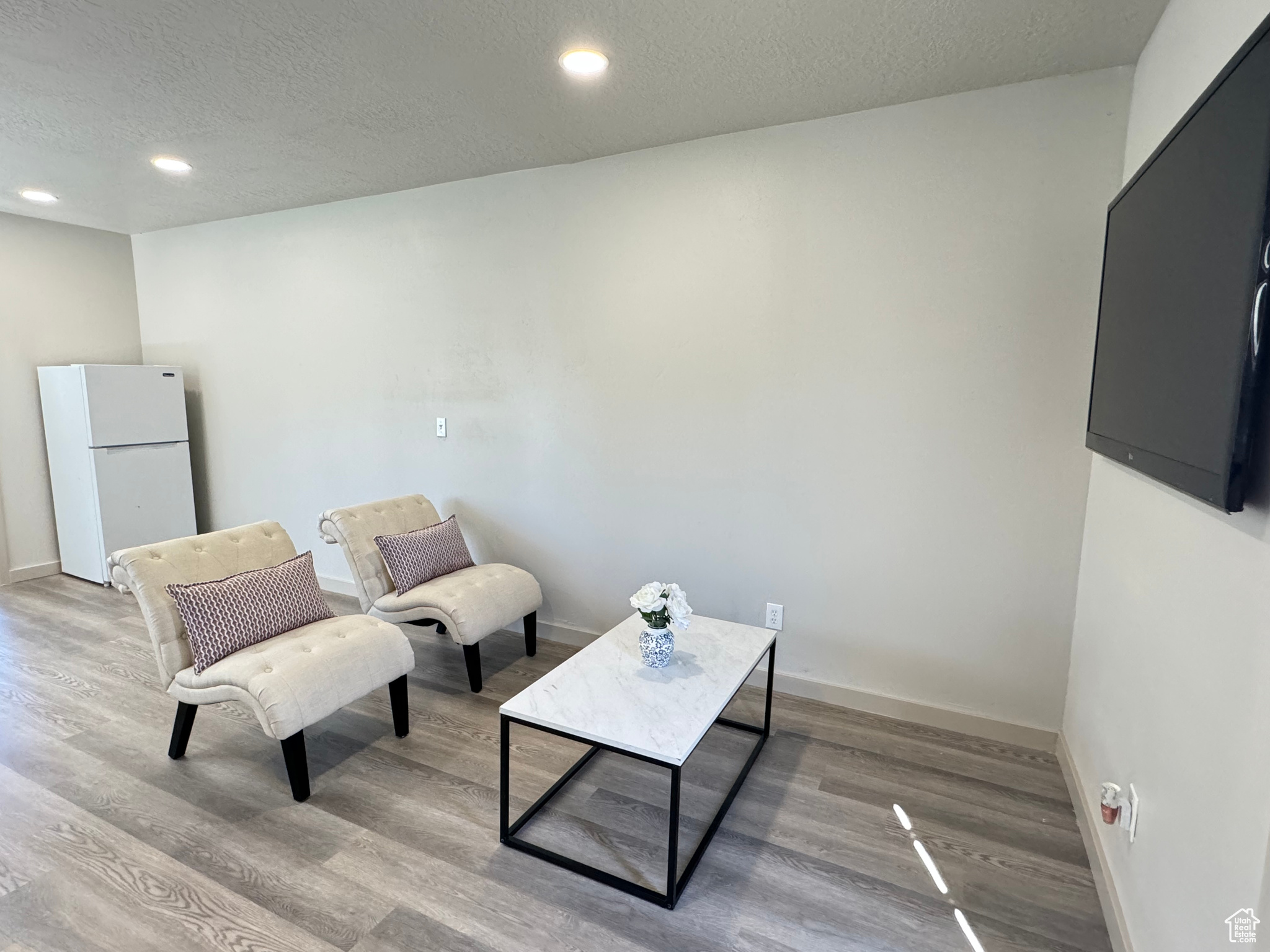 Sitting room with a textured ceiling and light hardwood / wood-style flooring