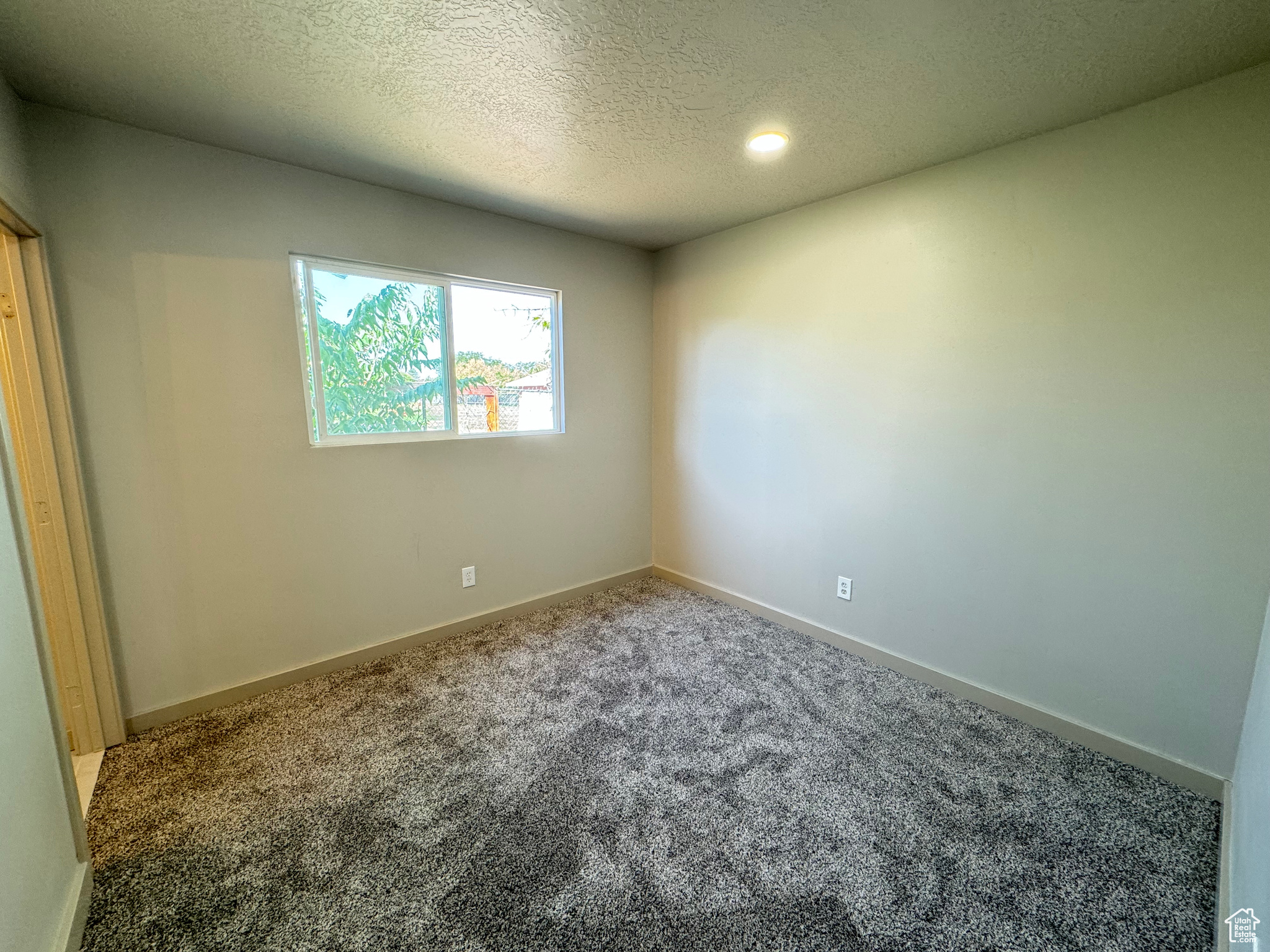 Unfurnished room featuring a textured ceiling and carpet