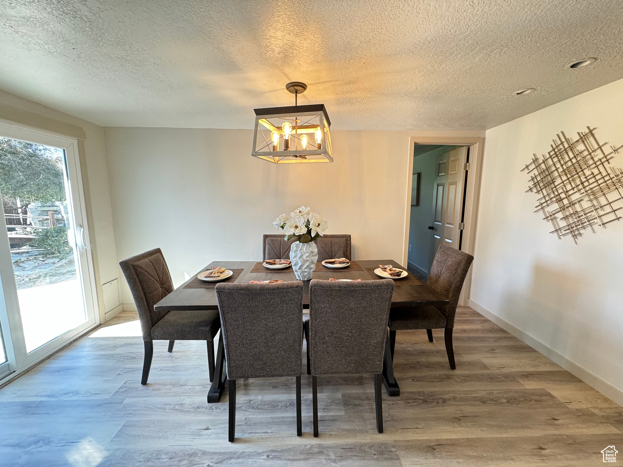 Dining space featuring a textured ceiling, a chandelier, and hardwood / wood-style floors