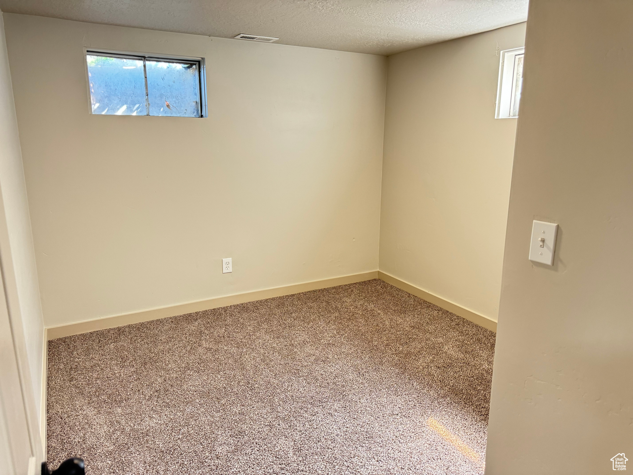 Carpeted empty room featuring a textured ceiling