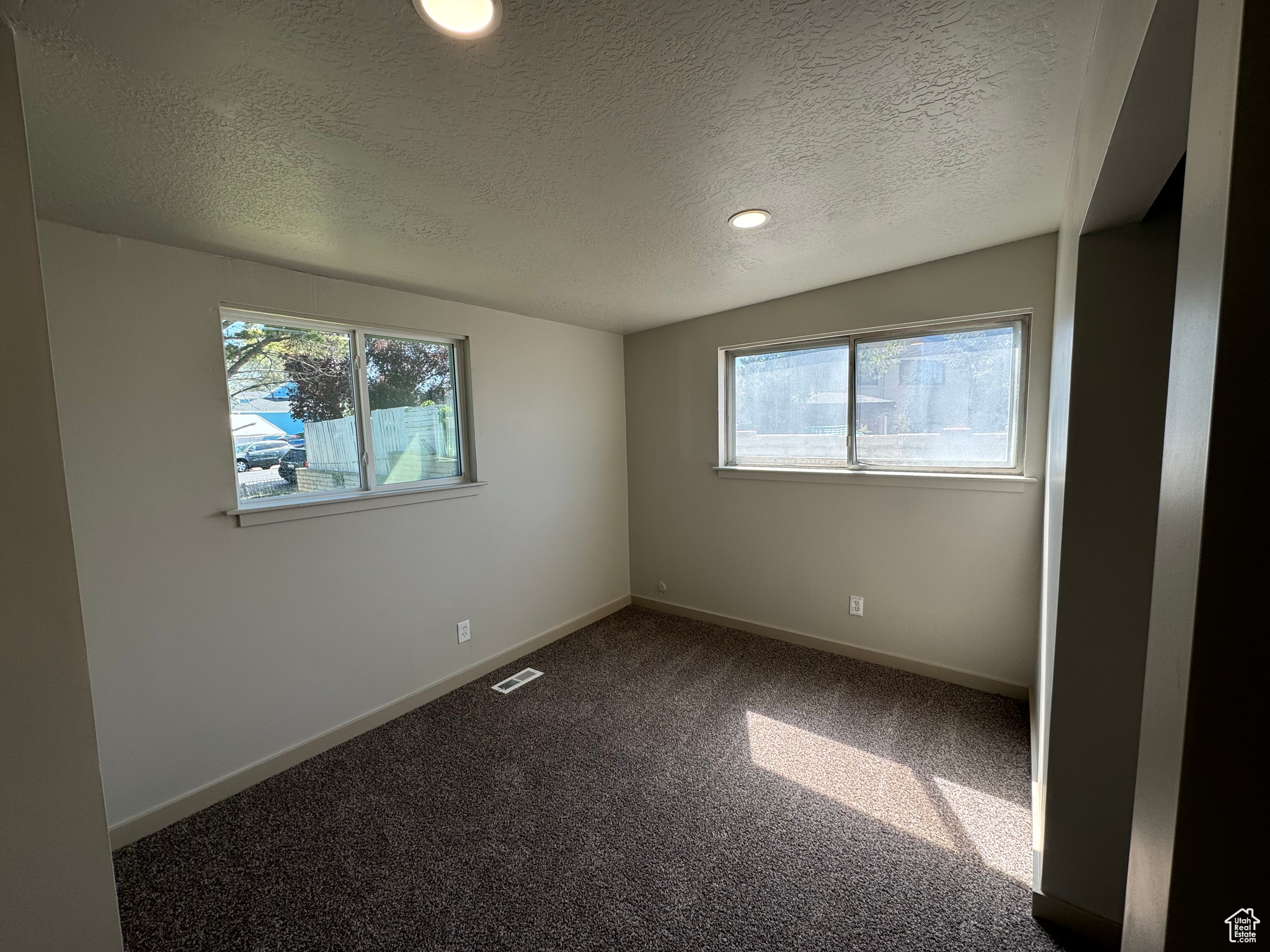 Carpeted empty room with a textured ceiling and a healthy amount of sunlight