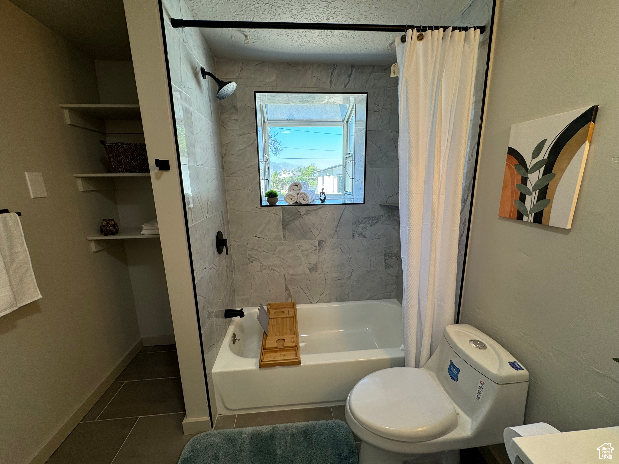 Bathroom featuring toilet, shower / tub combo with curtain, tile patterned floors, and a textured ceiling