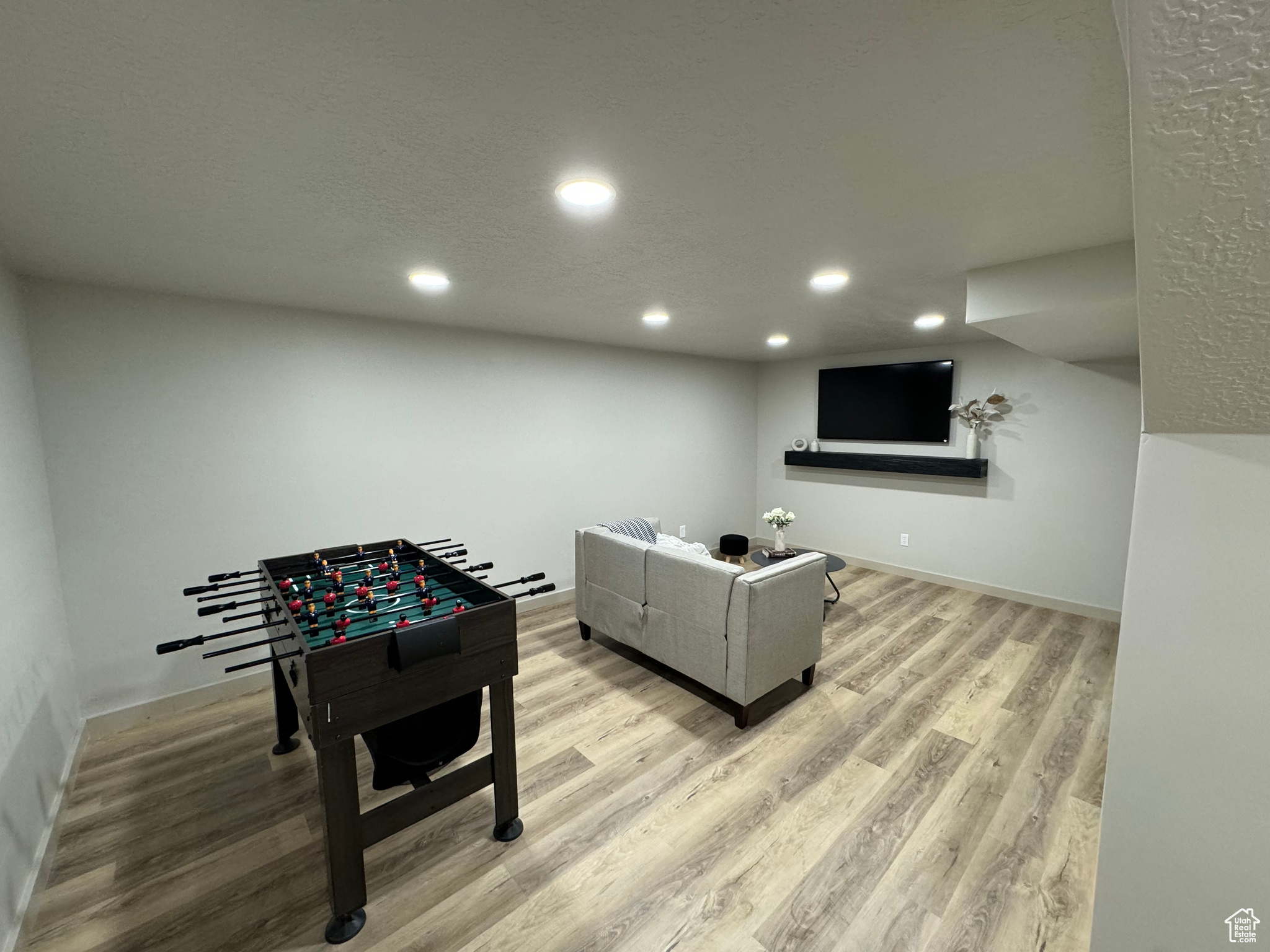 Recreation room featuring a textured ceiling and light hardwood / wood-style floors