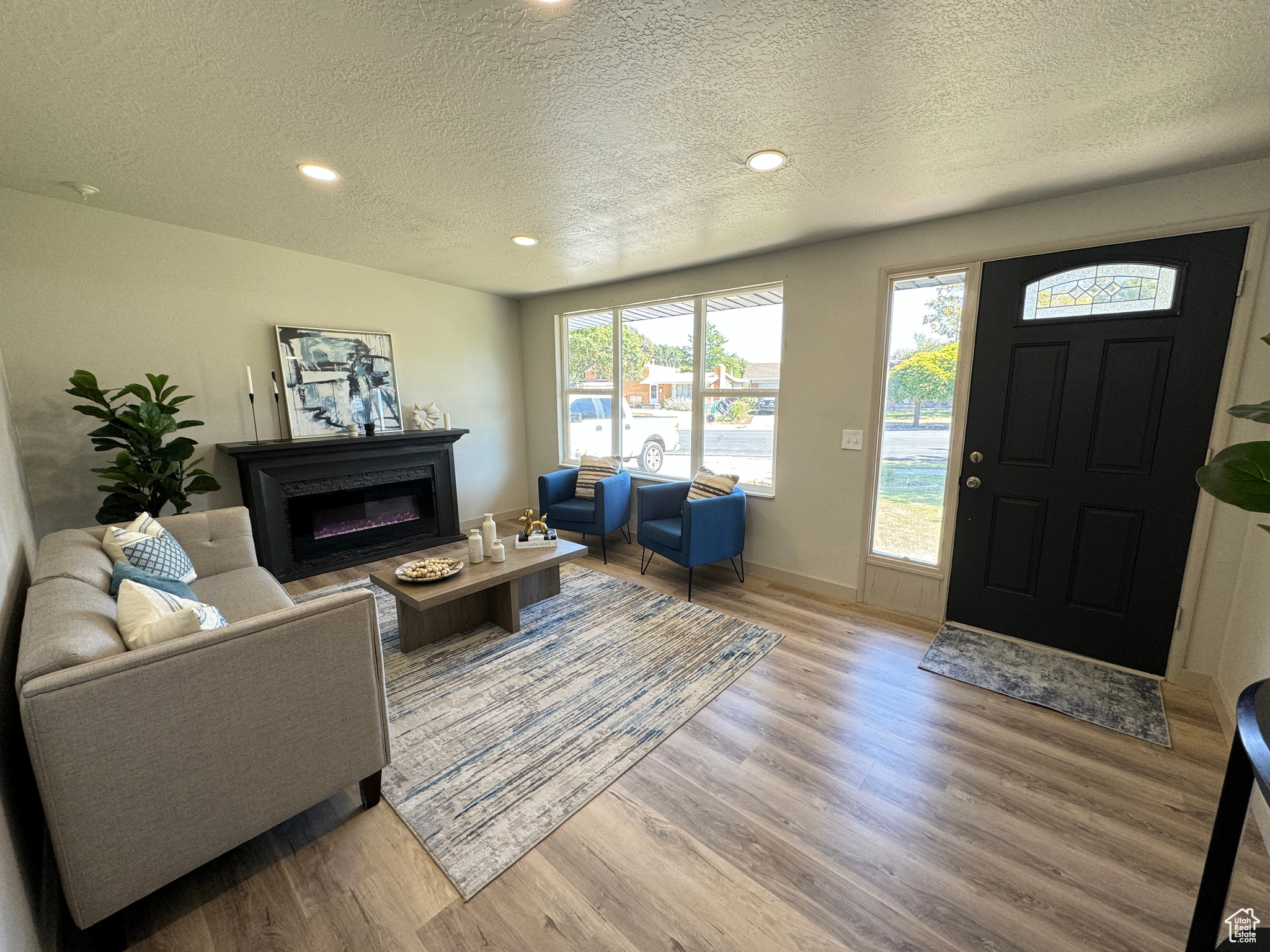 Living room with a textured ceiling and light hardwood / wood-style flooring