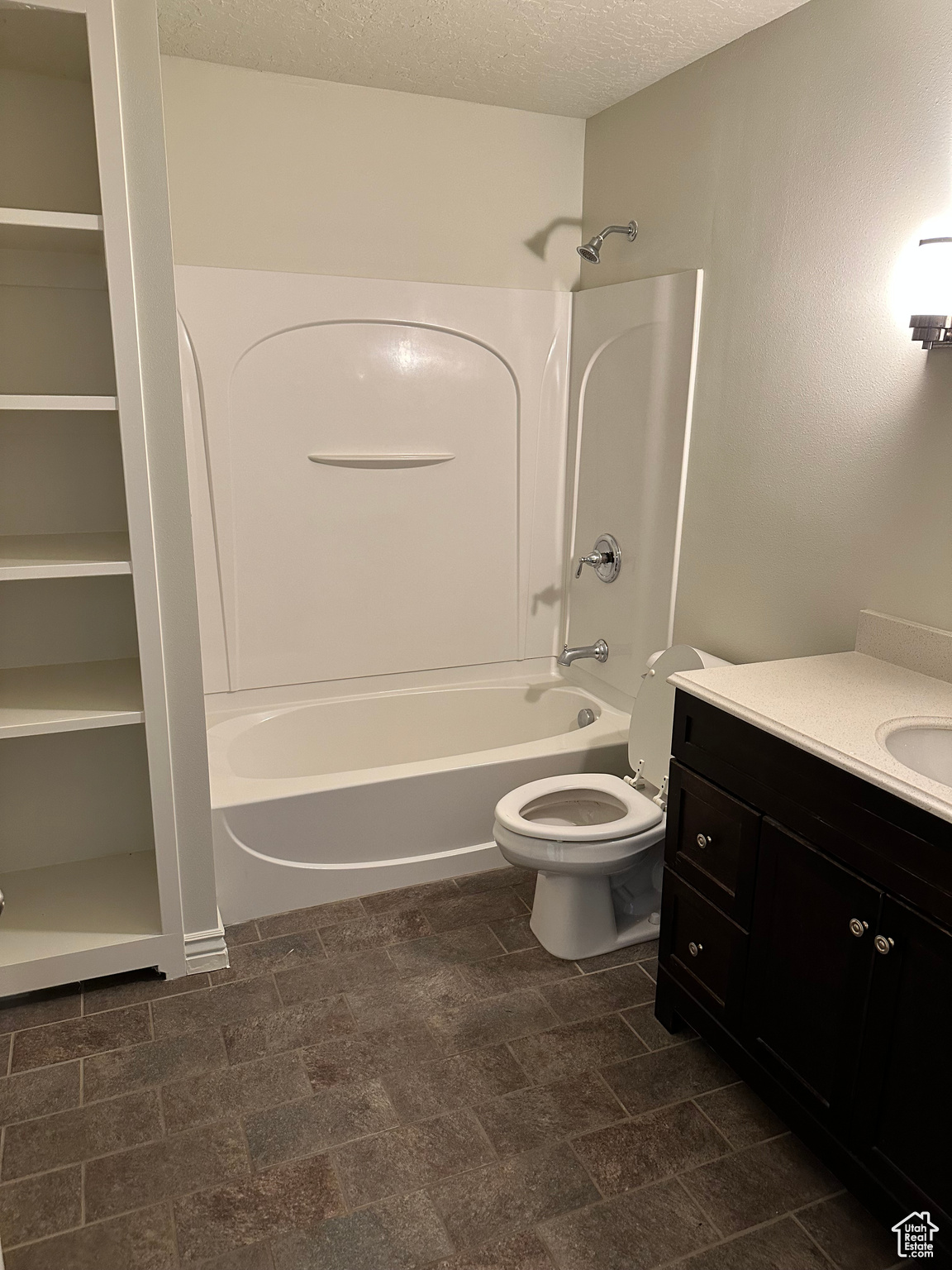 Full bathroom featuring a textured ceiling, vanity, toilet, and shower / bath combination