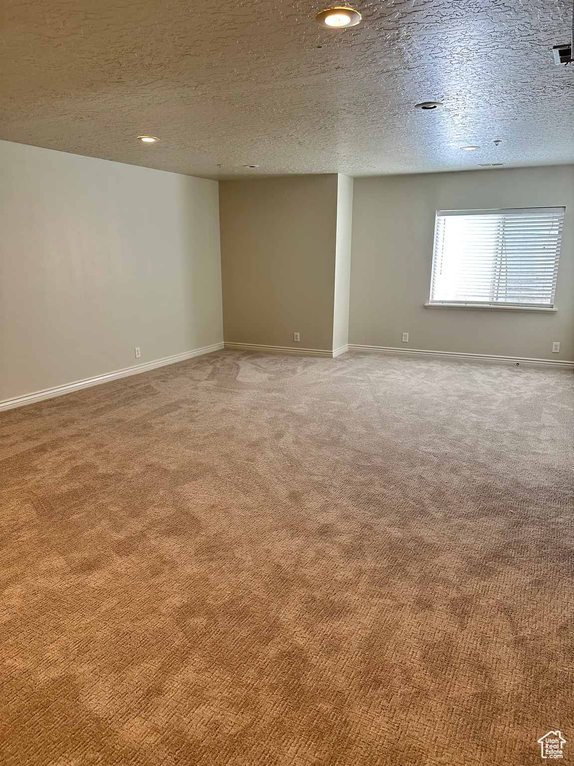 Carpeted spare room featuring a textured ceiling