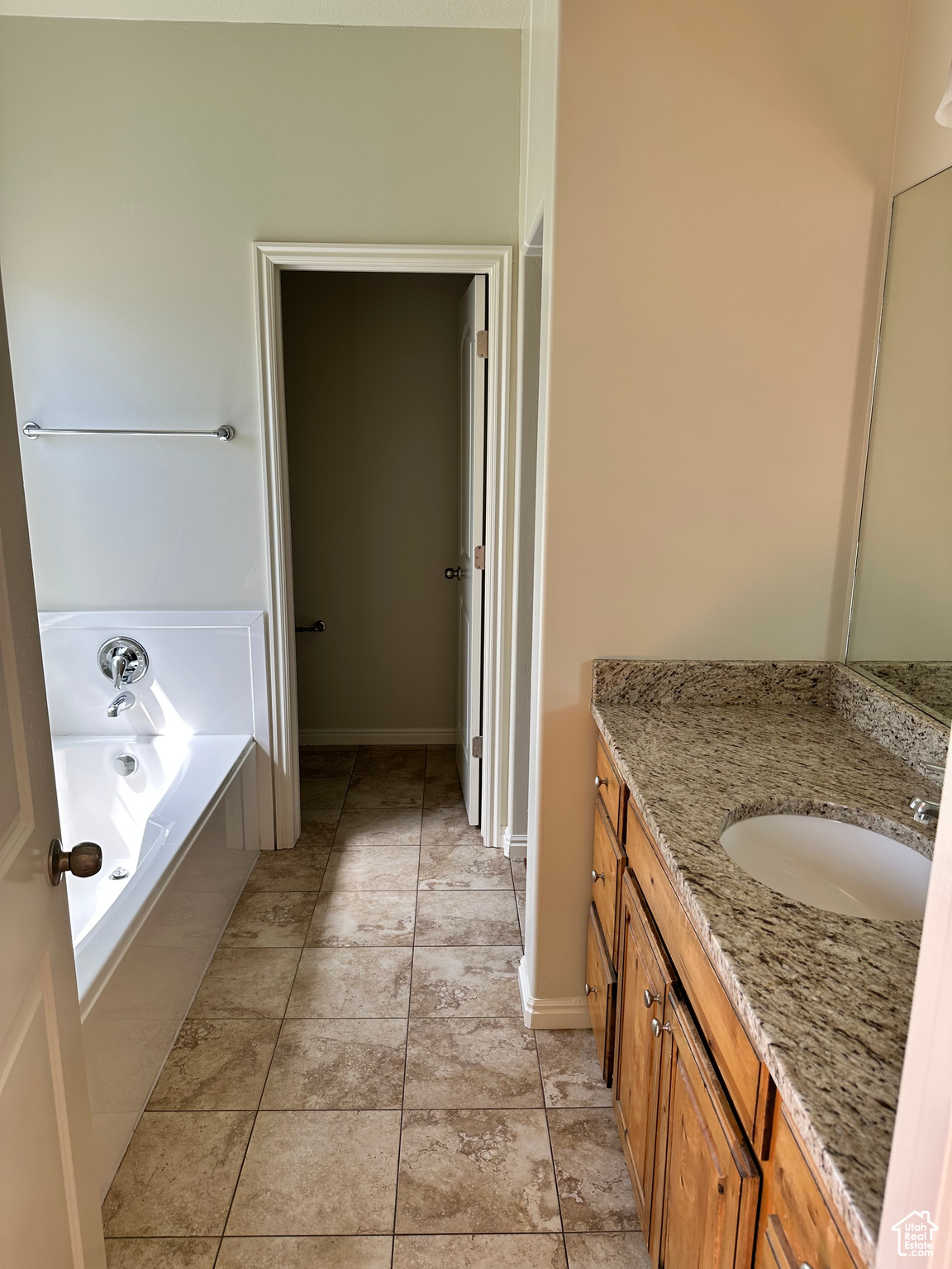 Bathroom with tile patterned flooring, vanity, and a relaxing tiled tub