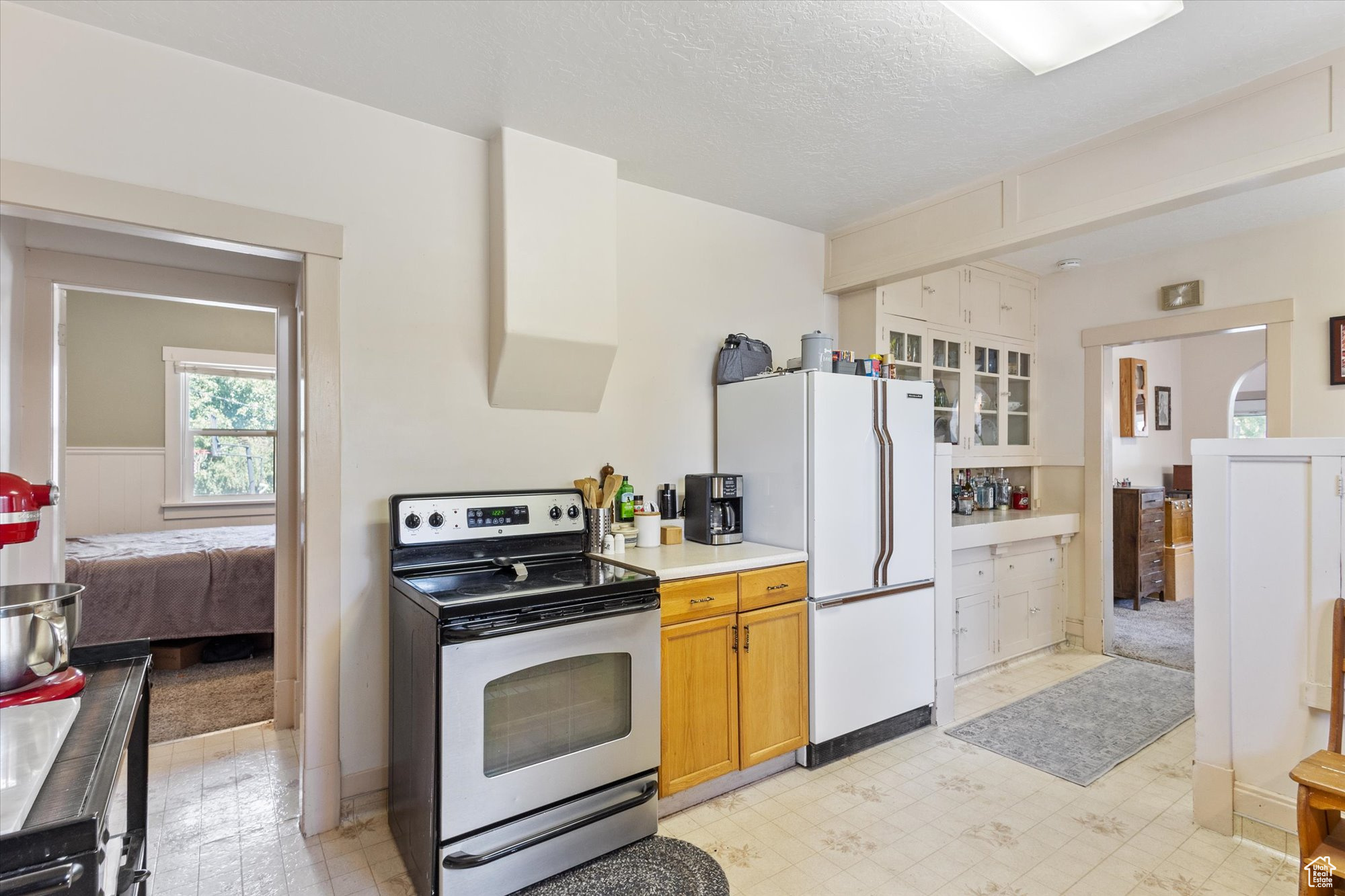 Kitchen with white refrigerator, stainless steel range with electric cooktop, and a textured ceiling