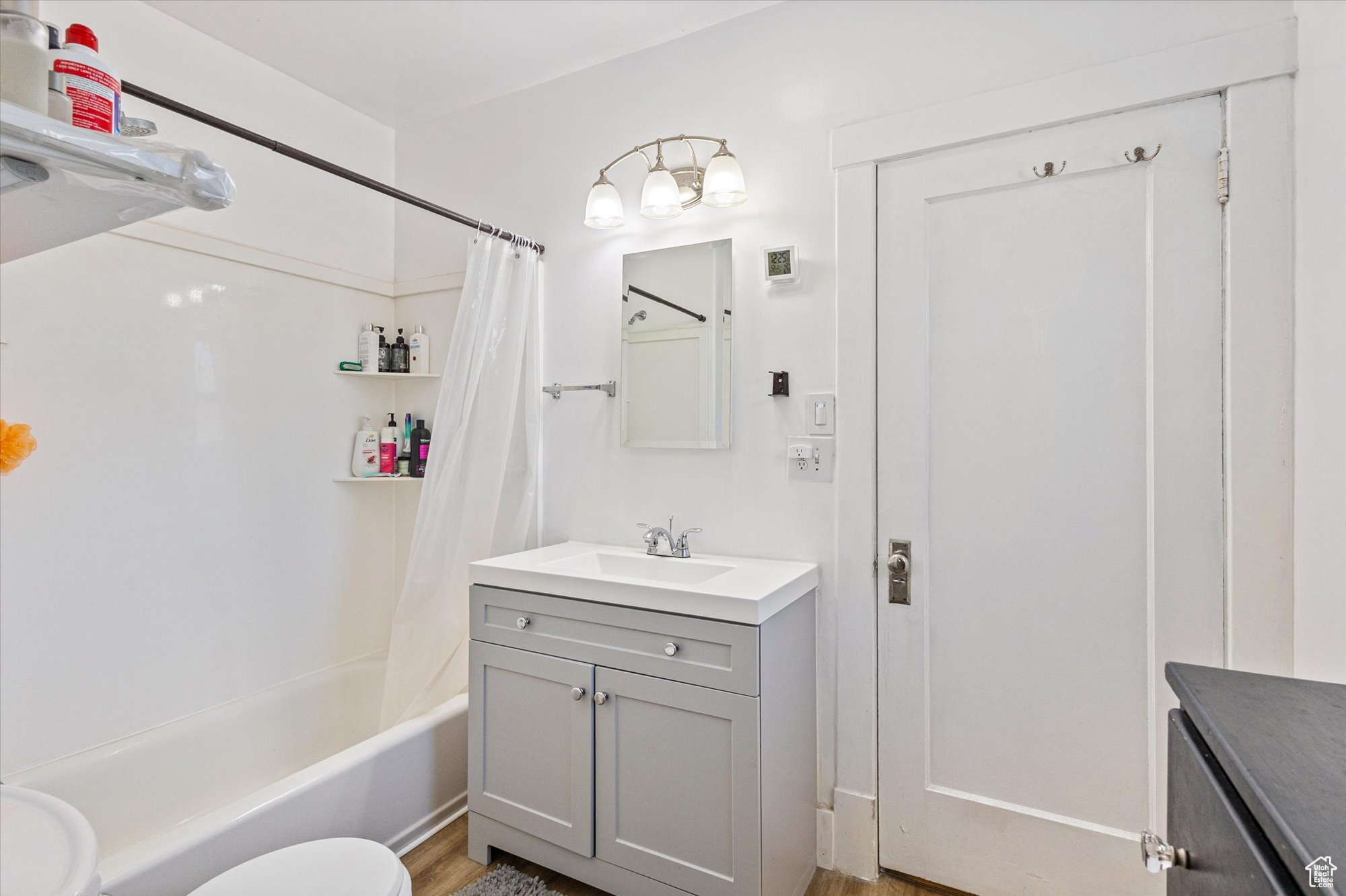 Full updated bathroom featuring shower / bath combo with shower curtain, hardwood / wood-style LVP floors, toilet, and vanity