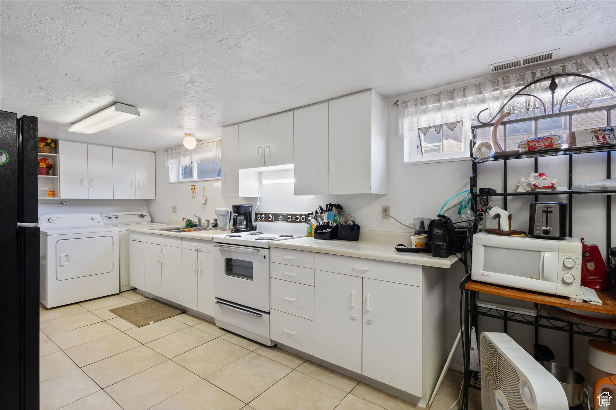 Kitchen featuring white cabinets, white appliances, independent washer and dryer, sink, and a textured ceiling