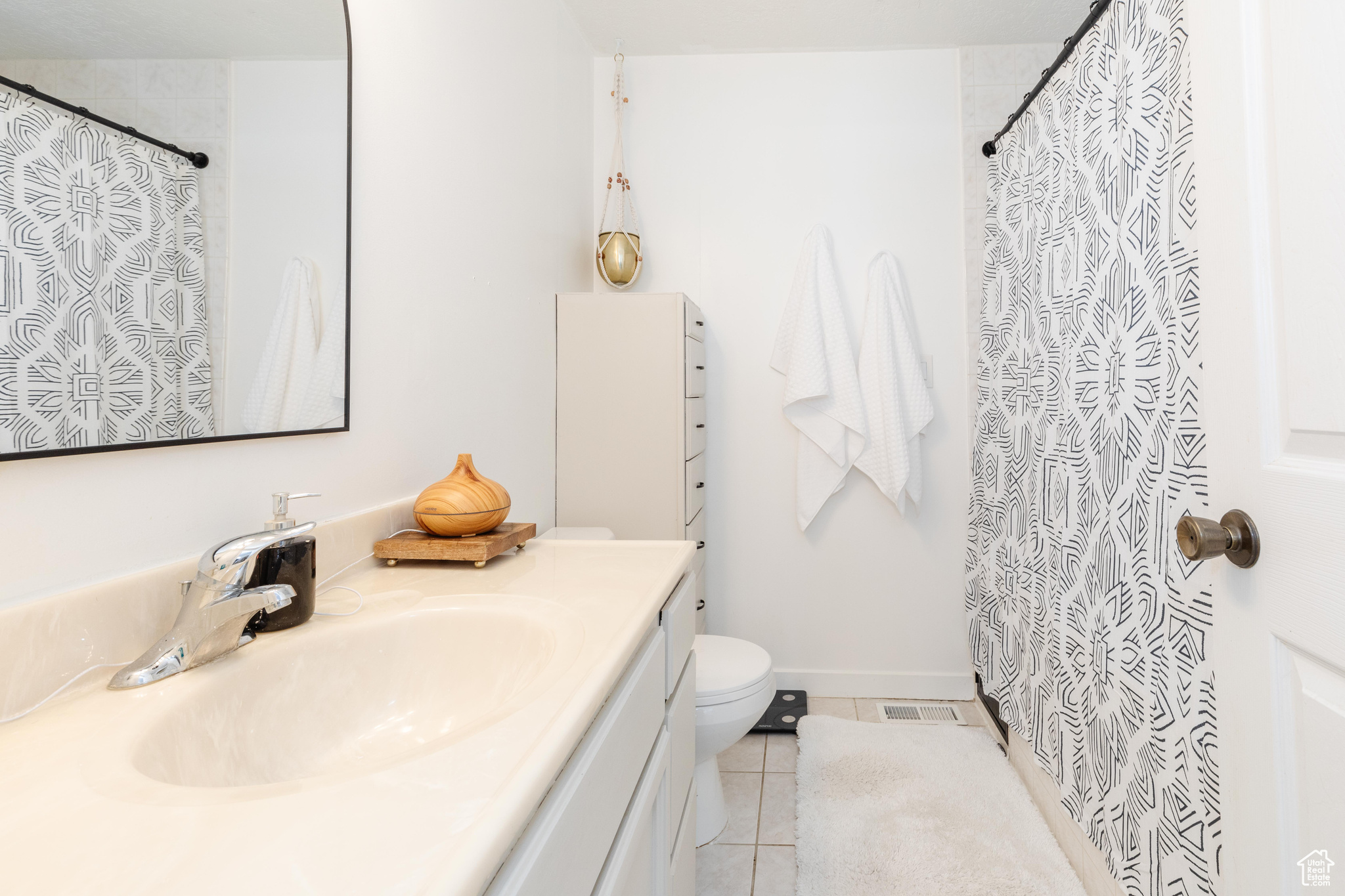 Bathroom featuring a shower with shower curtain, vanity, toilet, and tile patterned floors