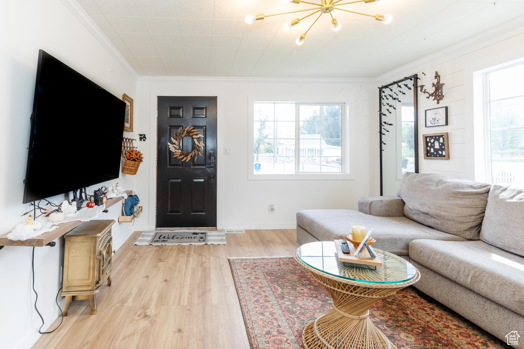 Living room with a notable chandelier, light wood-type flooring, and crown molding