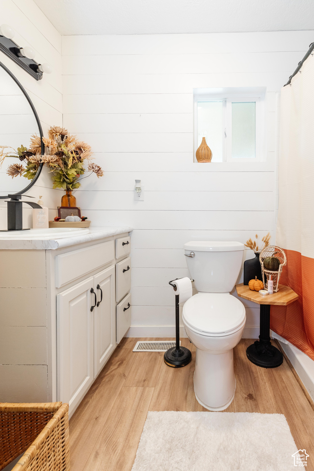 Bathroom featuring vanity, wood-type flooring, wooden walls, toilet, and a shower with shower curtain