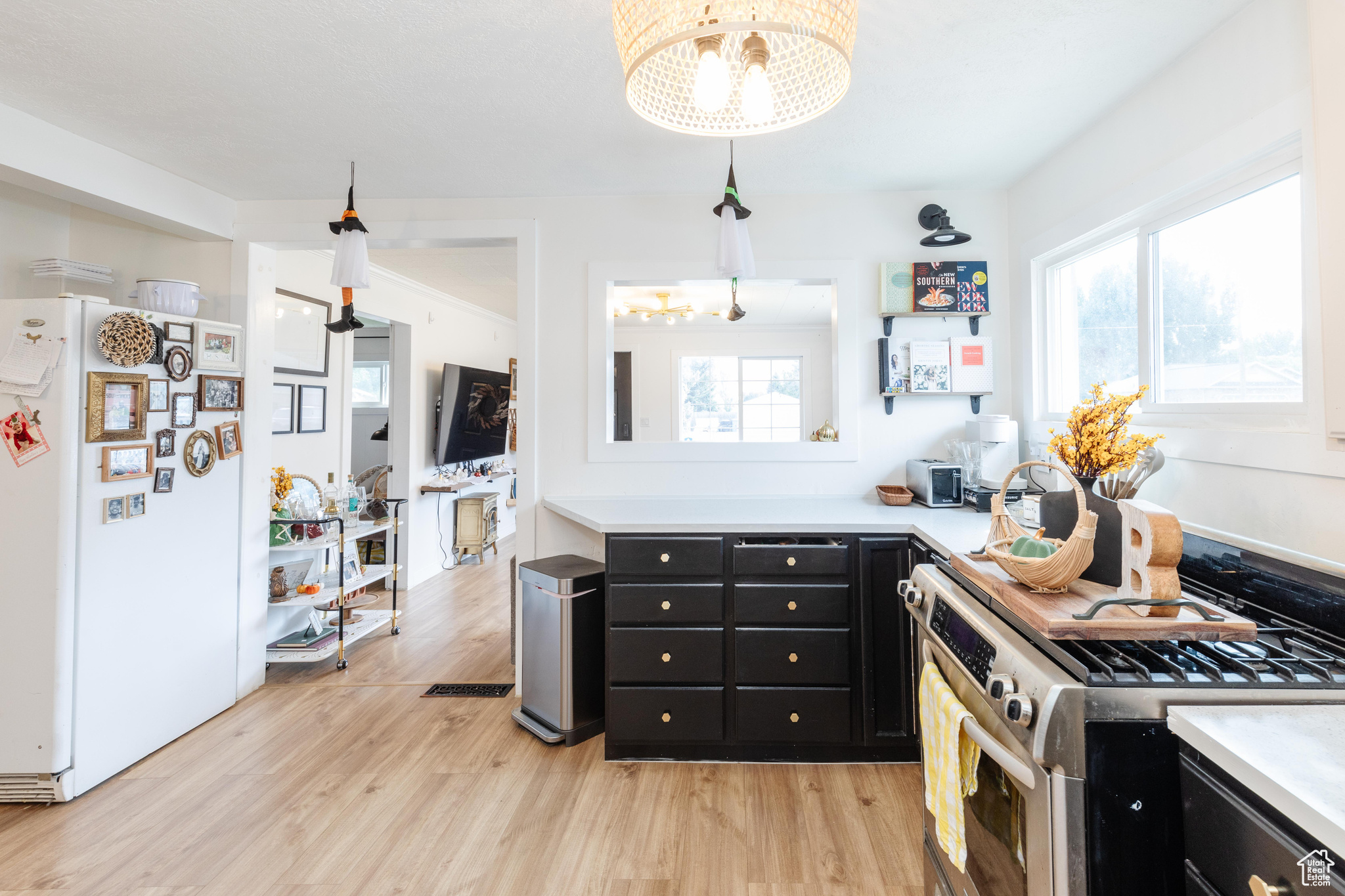 Kitchen featuring stainless steel stove, pendant lighting, white fridge, and a healthy amount of sunlight