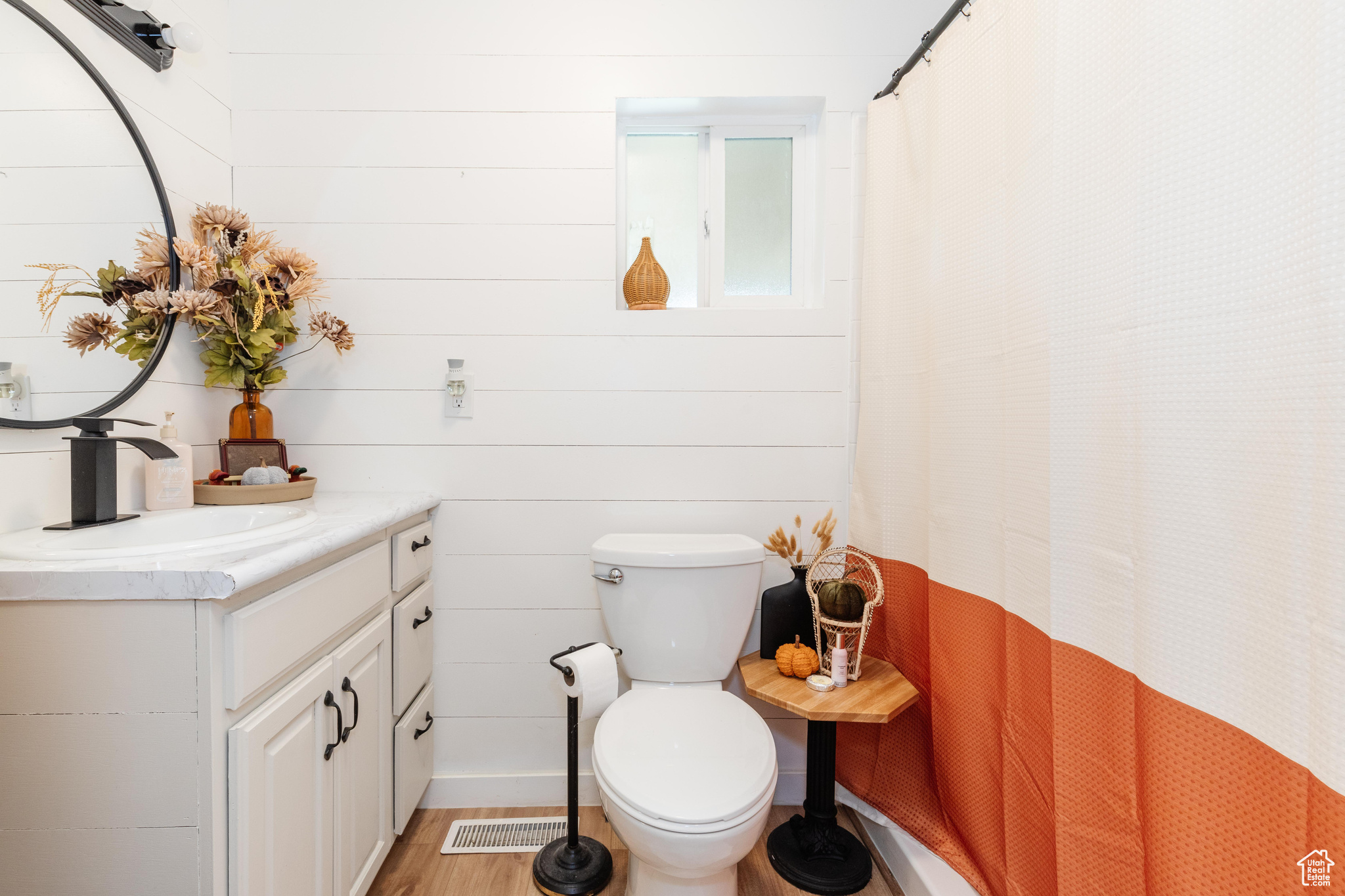 Bathroom with vanity, toilet, curtained shower, wooden walls, and hardwood / wood-style floors