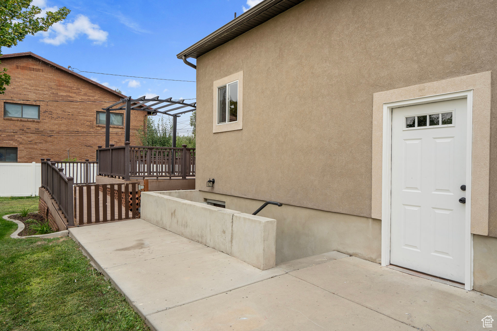 View of side of property featuring a wooden deck, a pergola, and a patio area