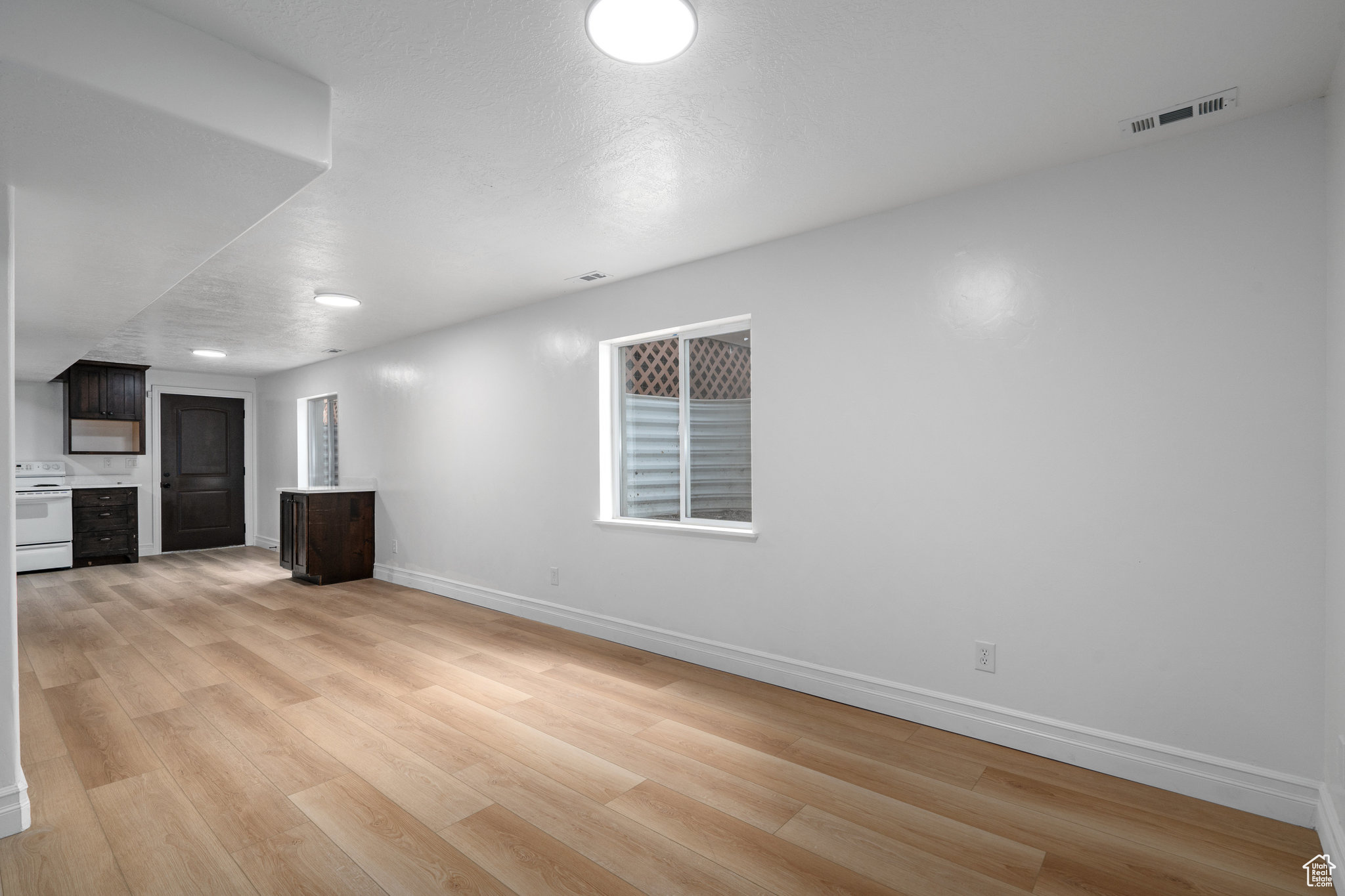 Unfurnished living room featuring a textured ceiling, light hardwood / wood-style floors, and plenty of natural light