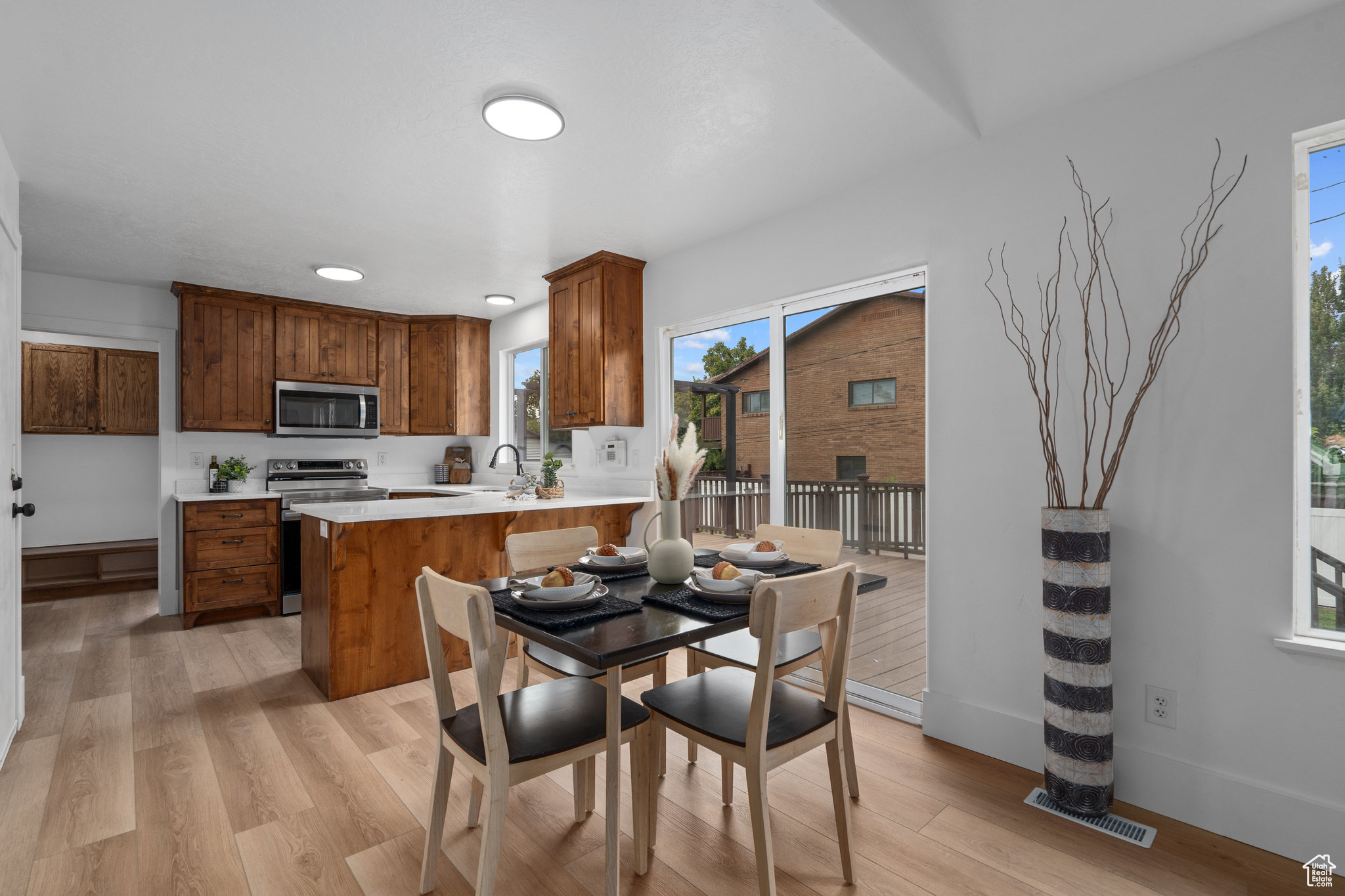 Kitchen with a breakfast bar area, stainless steel appliances, kitchen peninsula, and light hardwood / wood-style flooring