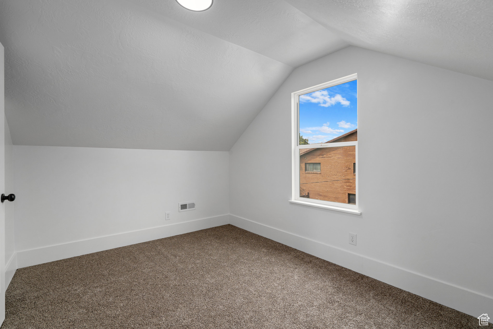 Additional living space with carpet floors, a textured ceiling, and lofted ceiling