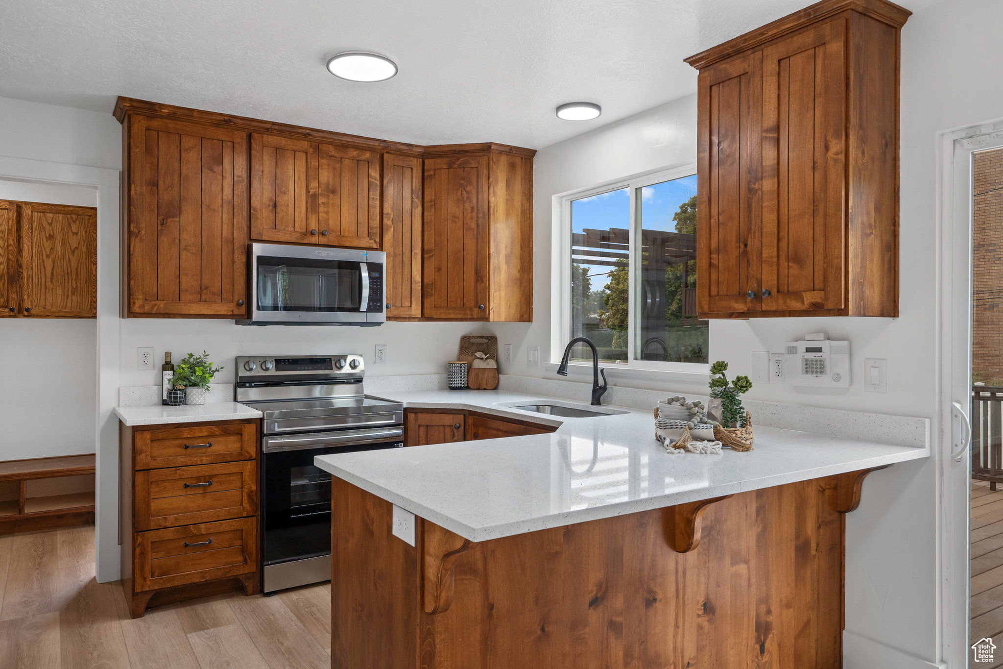 Kitchen featuring appliances with stainless steel finishes, kitchen peninsula, light wood-type flooring, and sink