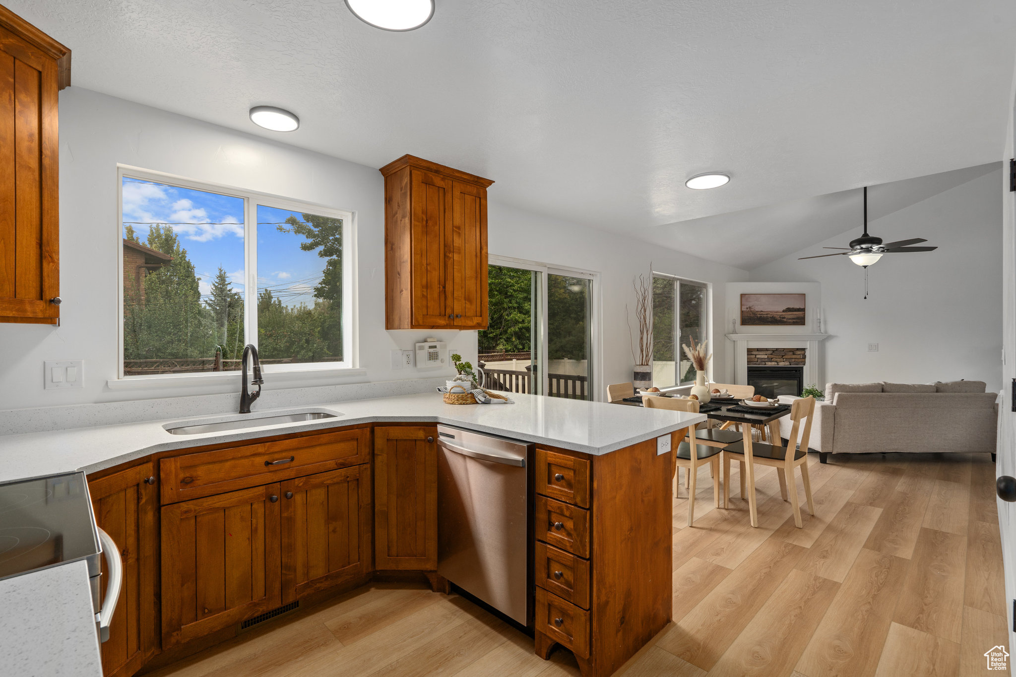 Kitchen with light wood-type flooring, lofted ceiling, sink, and stainless steel dishwasher