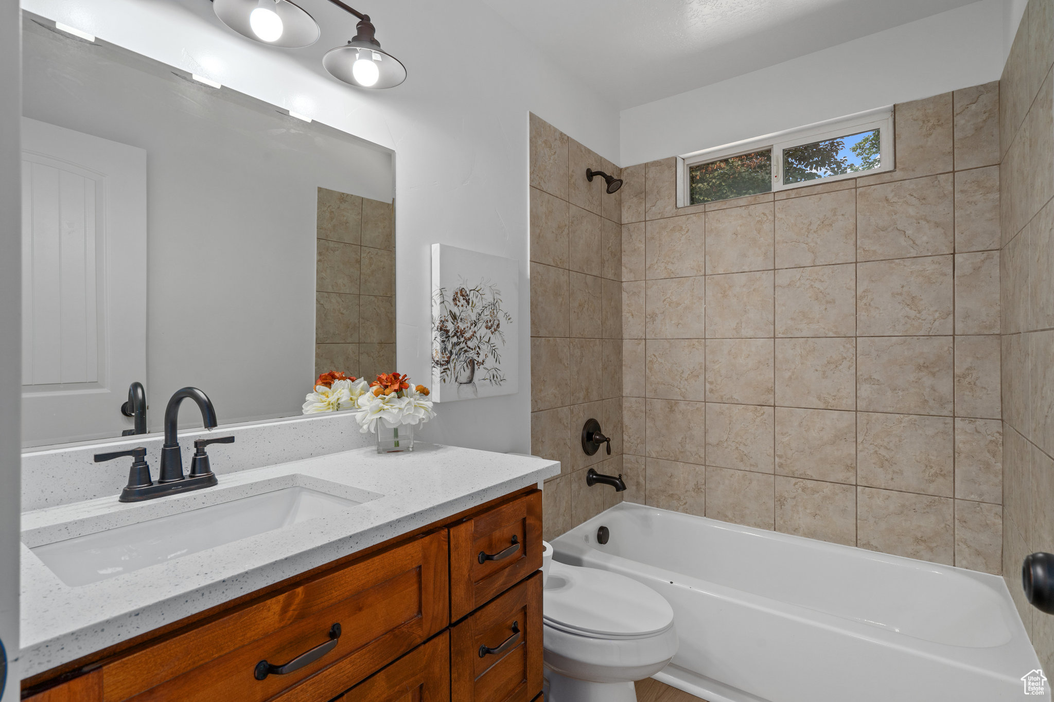 Full bathroom with tiled shower / bath combo, vanity, and toilet