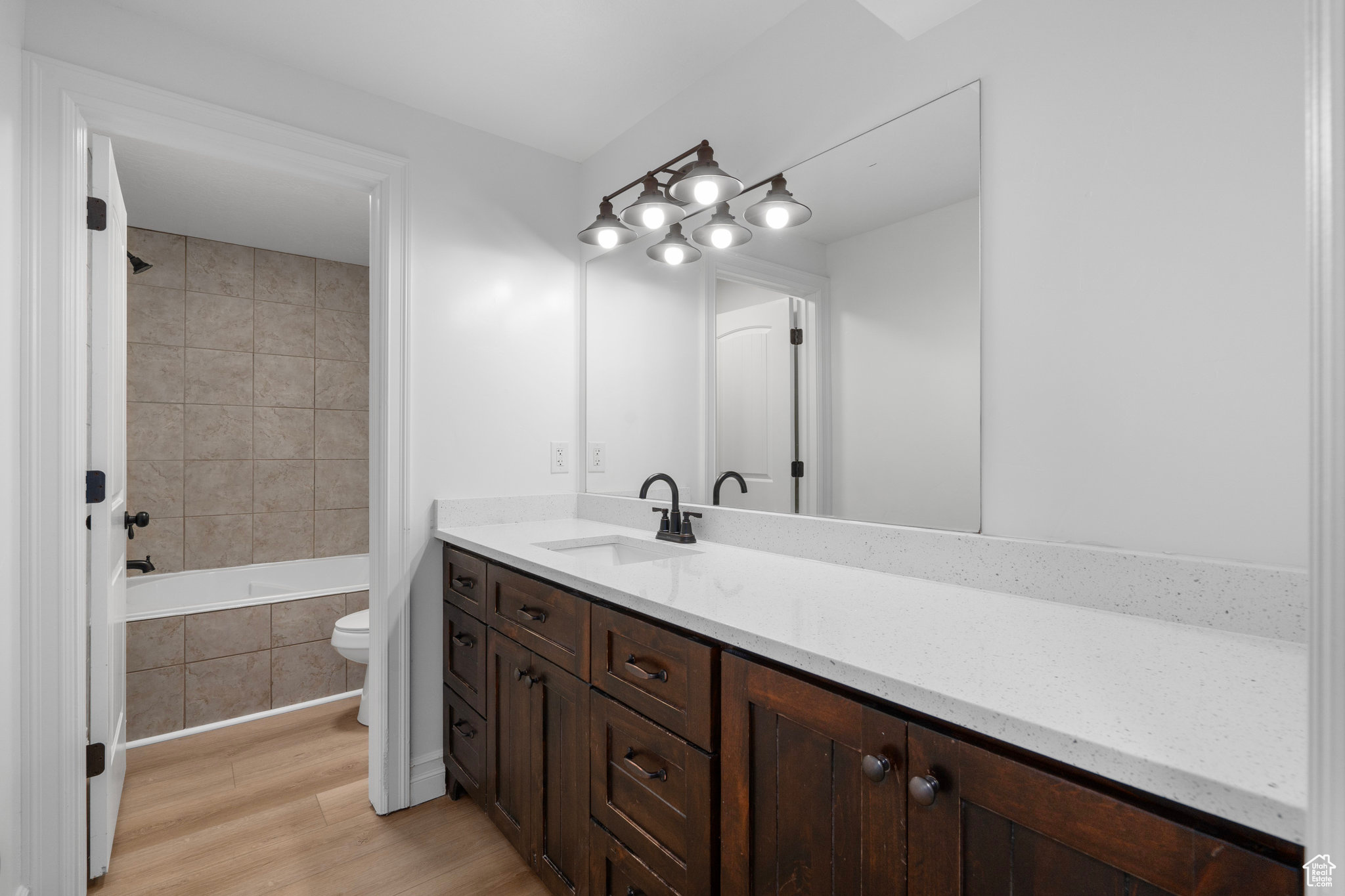 Full bathroom featuring hardwood / wood-style flooring, vanity, toilet, and tiled shower / bath