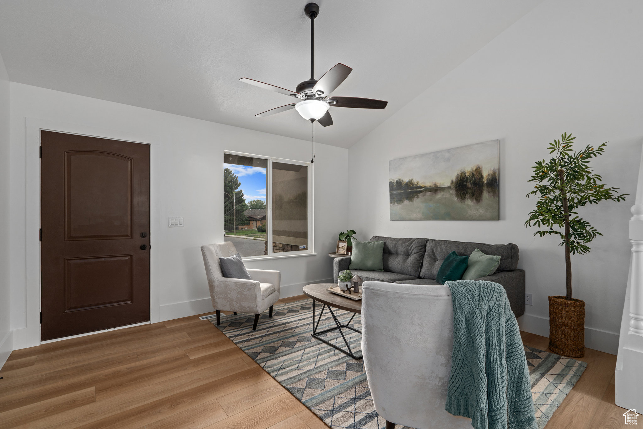 Living room featuring wood-type flooring, vaulted ceiling, and ceiling fan