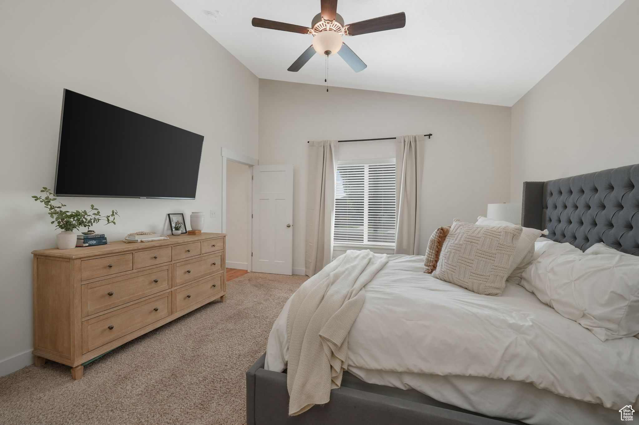 Bedroom featuring ceiling fan, light carpet, and vaulted ceiling