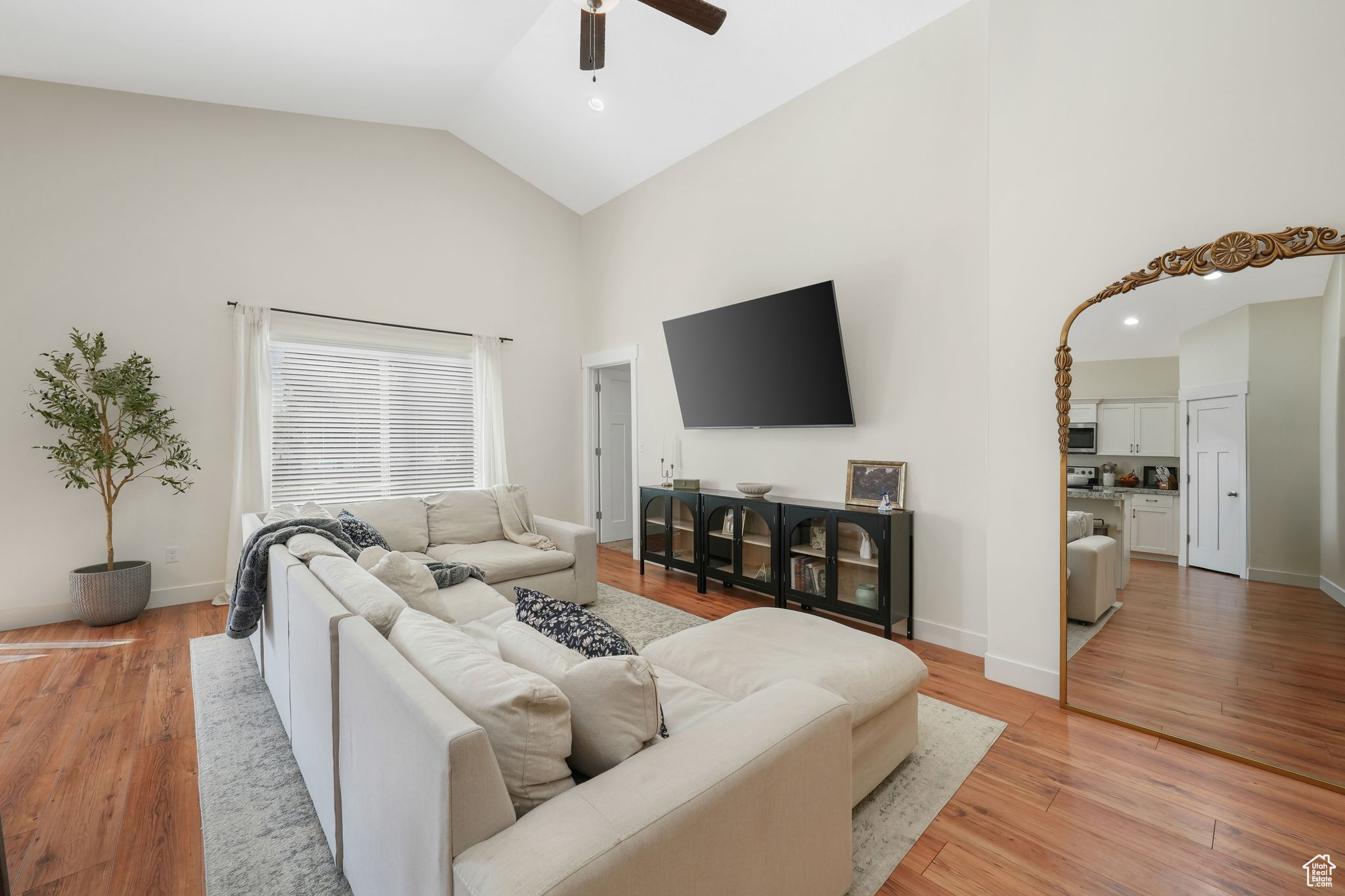 Living room with high vaulted ceiling, light hardwood / wood-style flooring, and ceiling fan