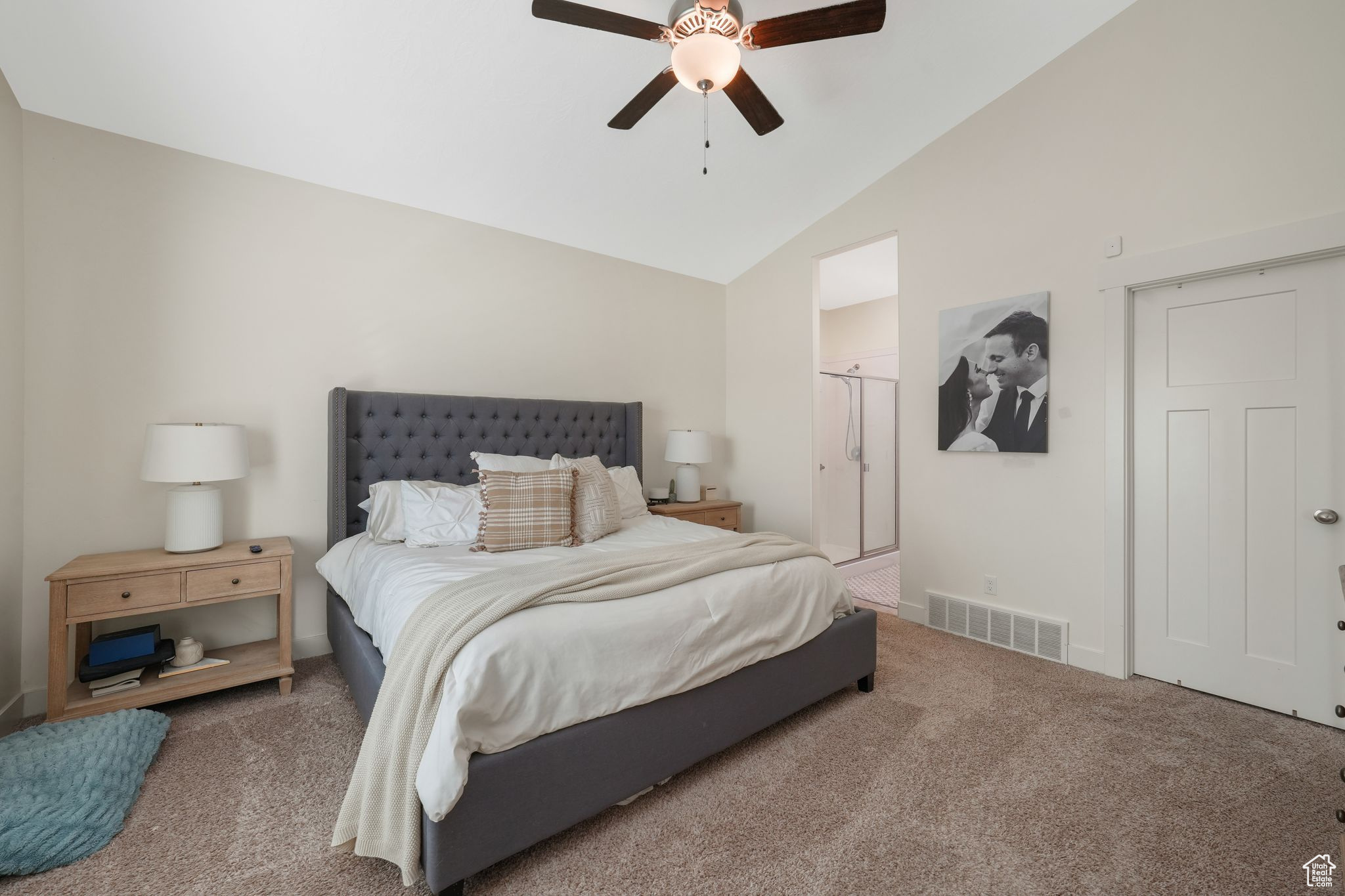 Carpeted bedroom featuring ceiling fan and vaulted ceiling