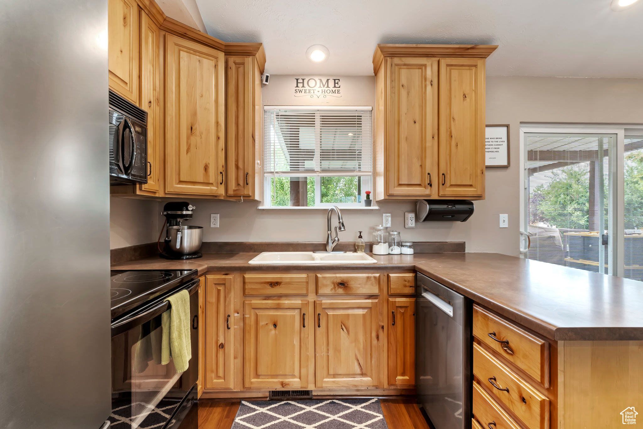 Kitchen featuring wood-type flooring, black appliances, kitchen peninsula, and sink