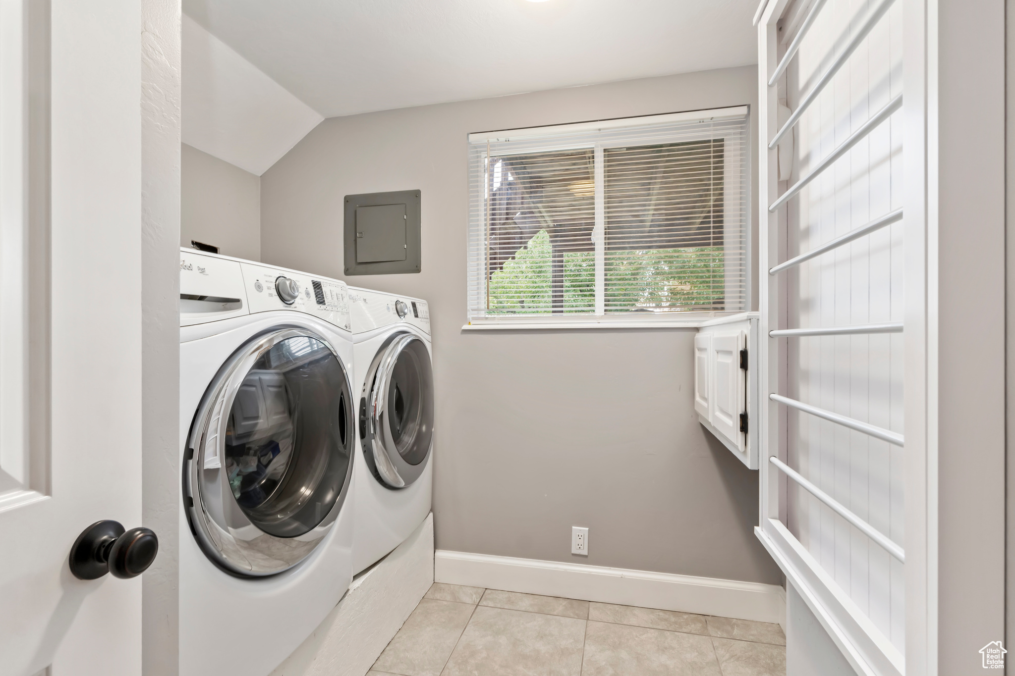 Laundry room featuring washer and clothes dryer, electric panel, and light tile patterned floors