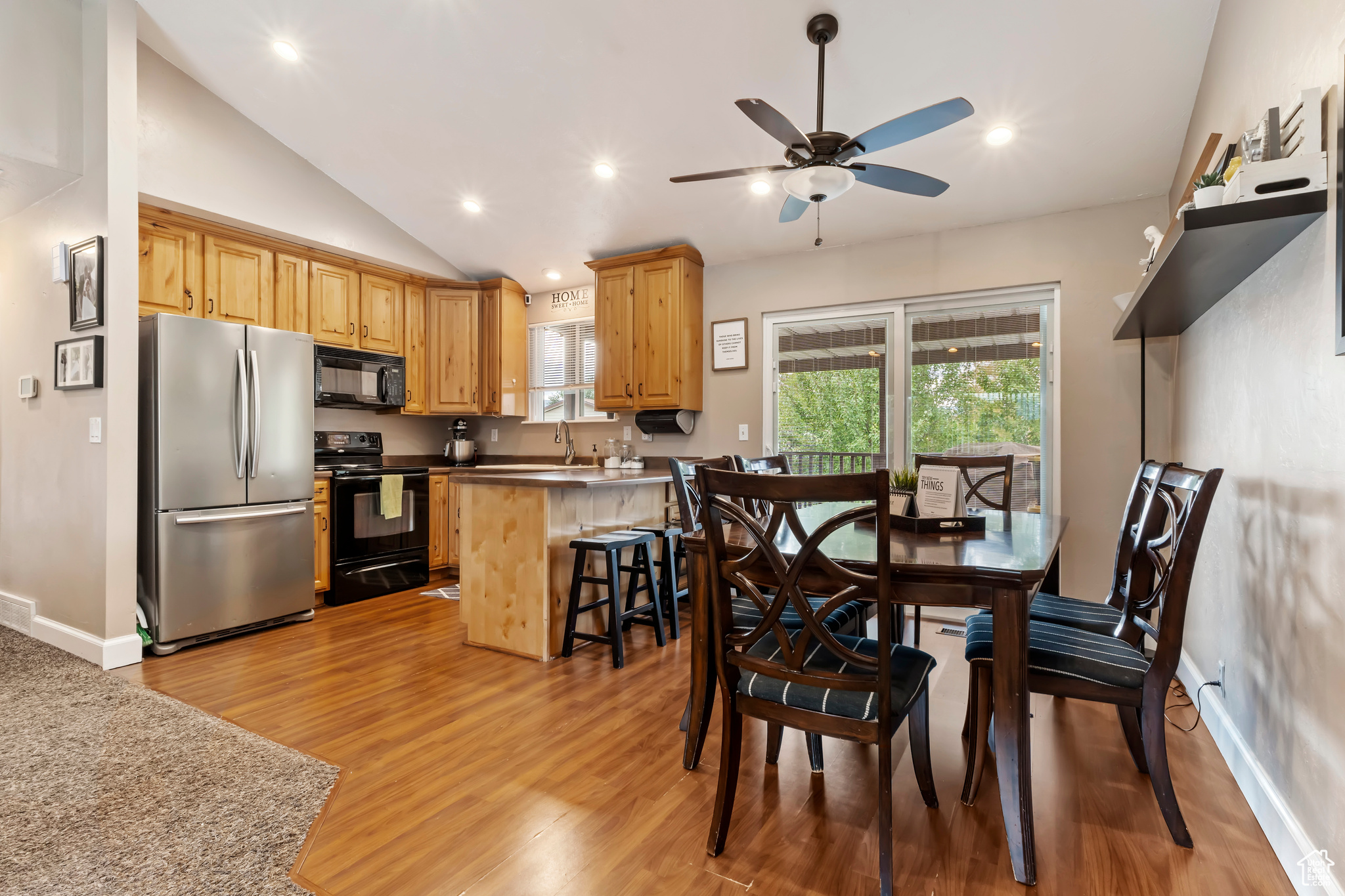 Dining room featuring light wood-type flooring, vaulted ceiling, sink, and ceiling fan