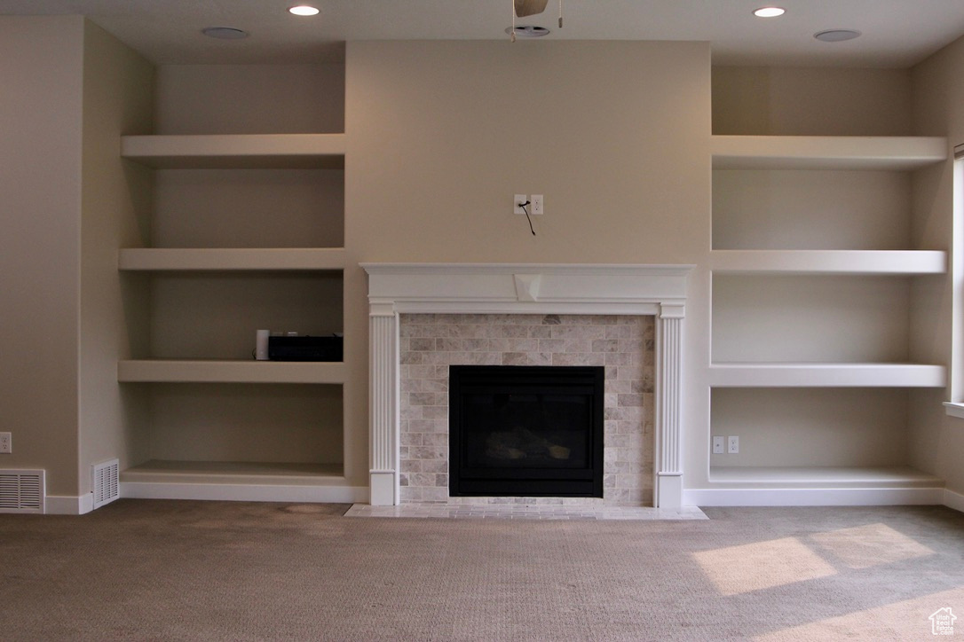 Unfurnished living room with built in shelves, carpet floors, and a brick fireplace