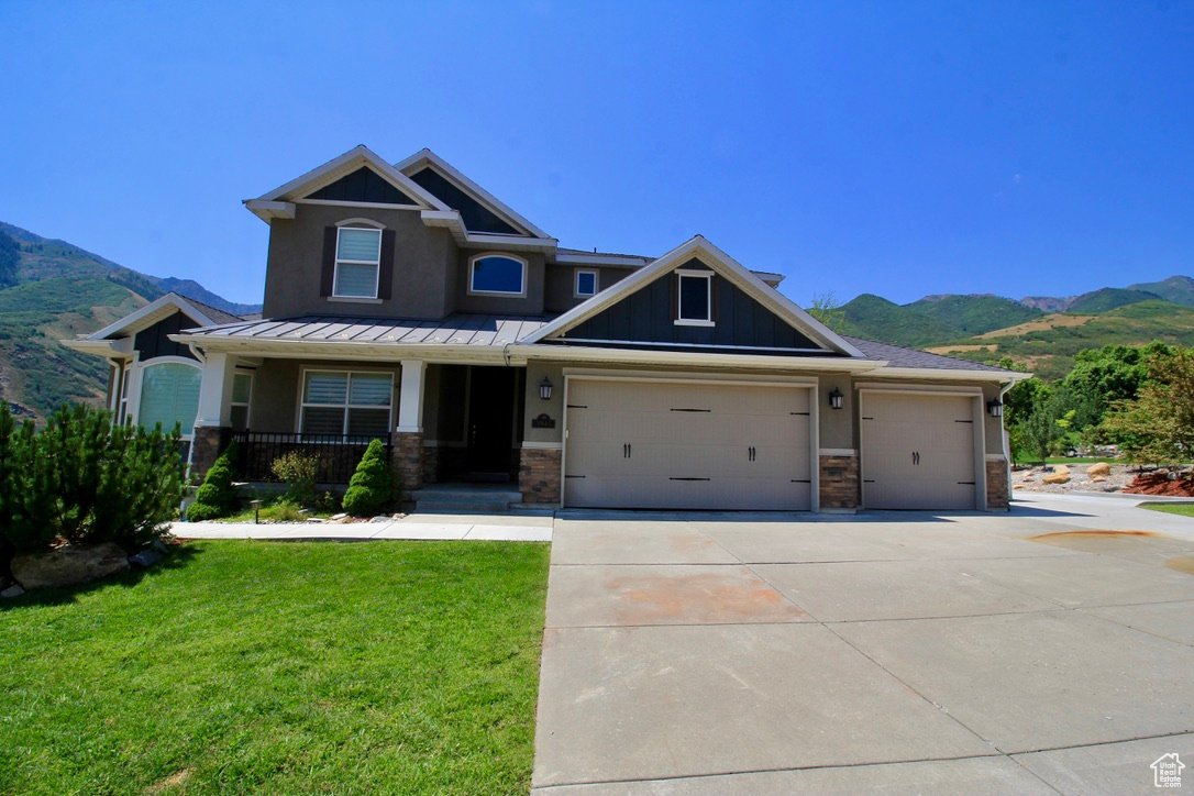 Craftsman house with a mountain view, a garage, a front yard, and covered porch