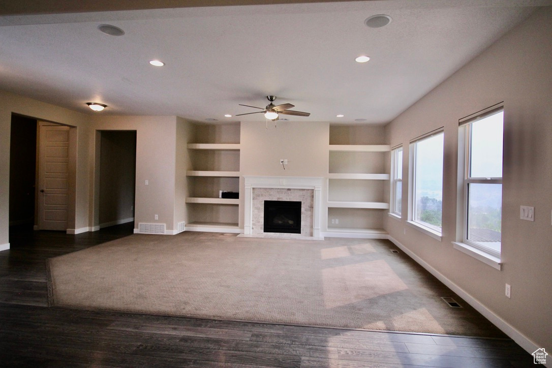 The great room awaits your personal touch; featuring built in shelves, a premium fireplace, a ceiling fan, and dark hardwood / wood-style floors, there is plenty of room for you to make this house your home.