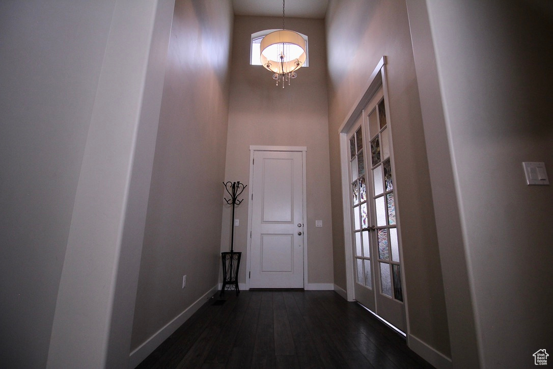 Interior space with an inviting chandelier, wood-style floors, and a towering ceiling