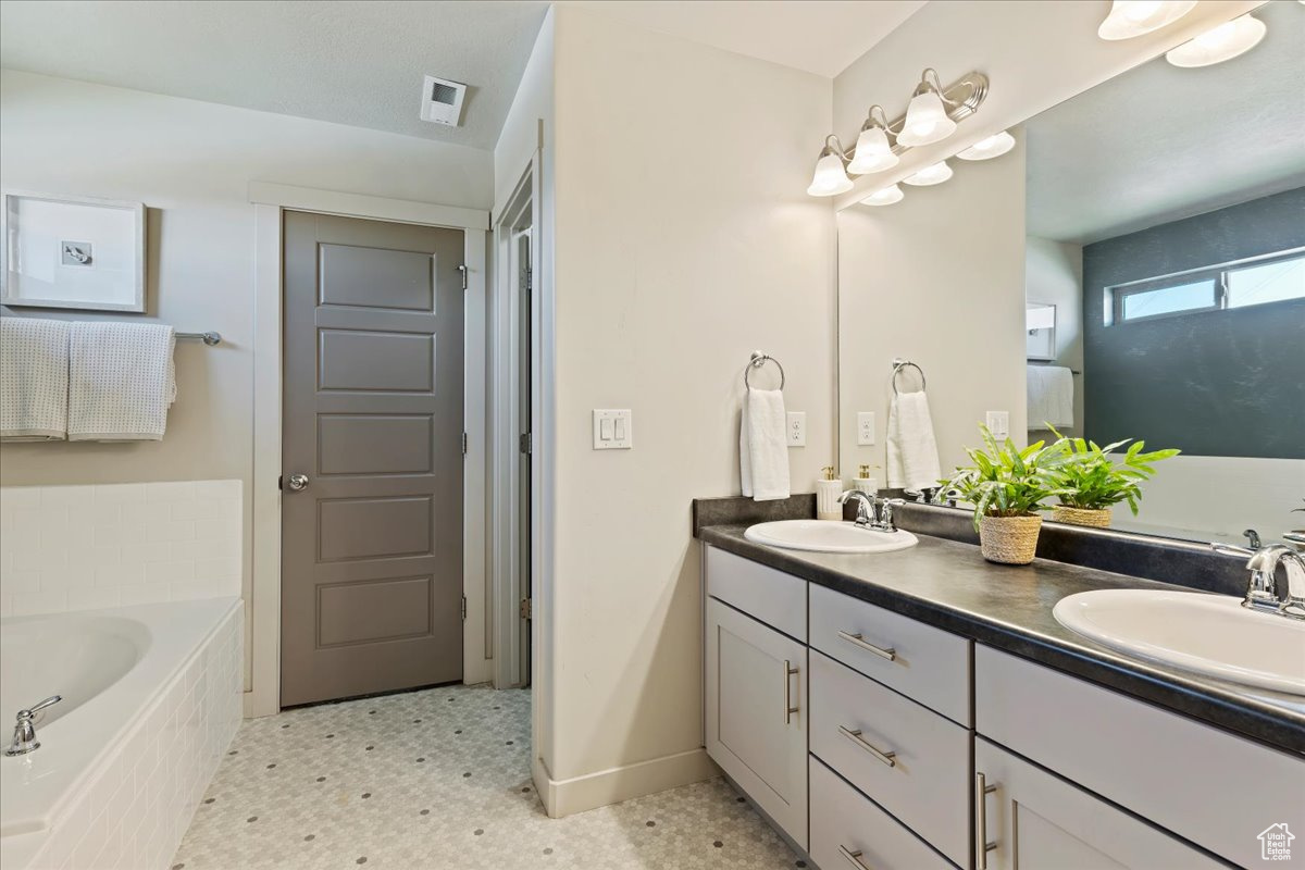 Primary bathroom with dual vanity, separate tub and shower, private toilet and walk-in closet